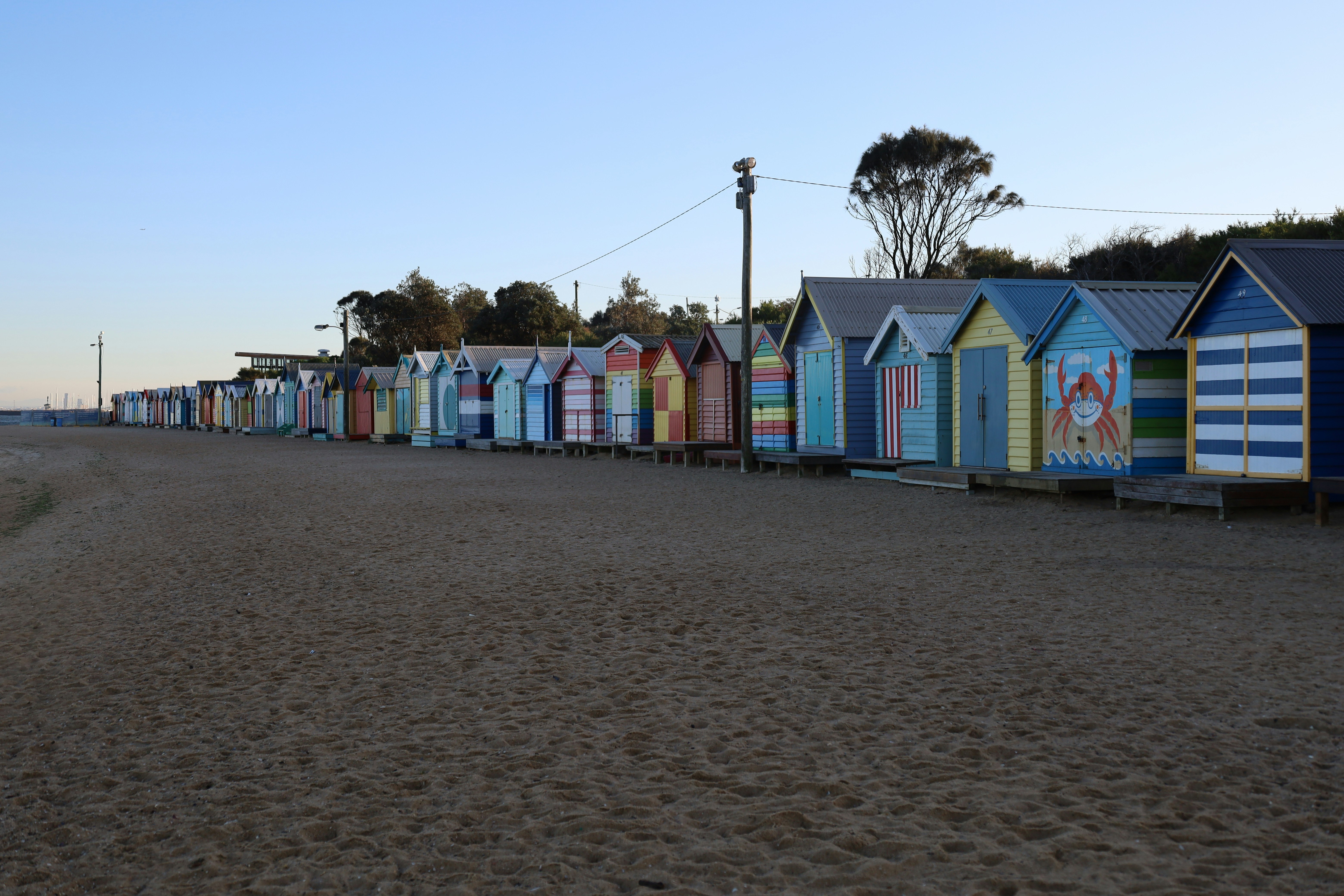 Row of colorful beach huts on a sandy beach.