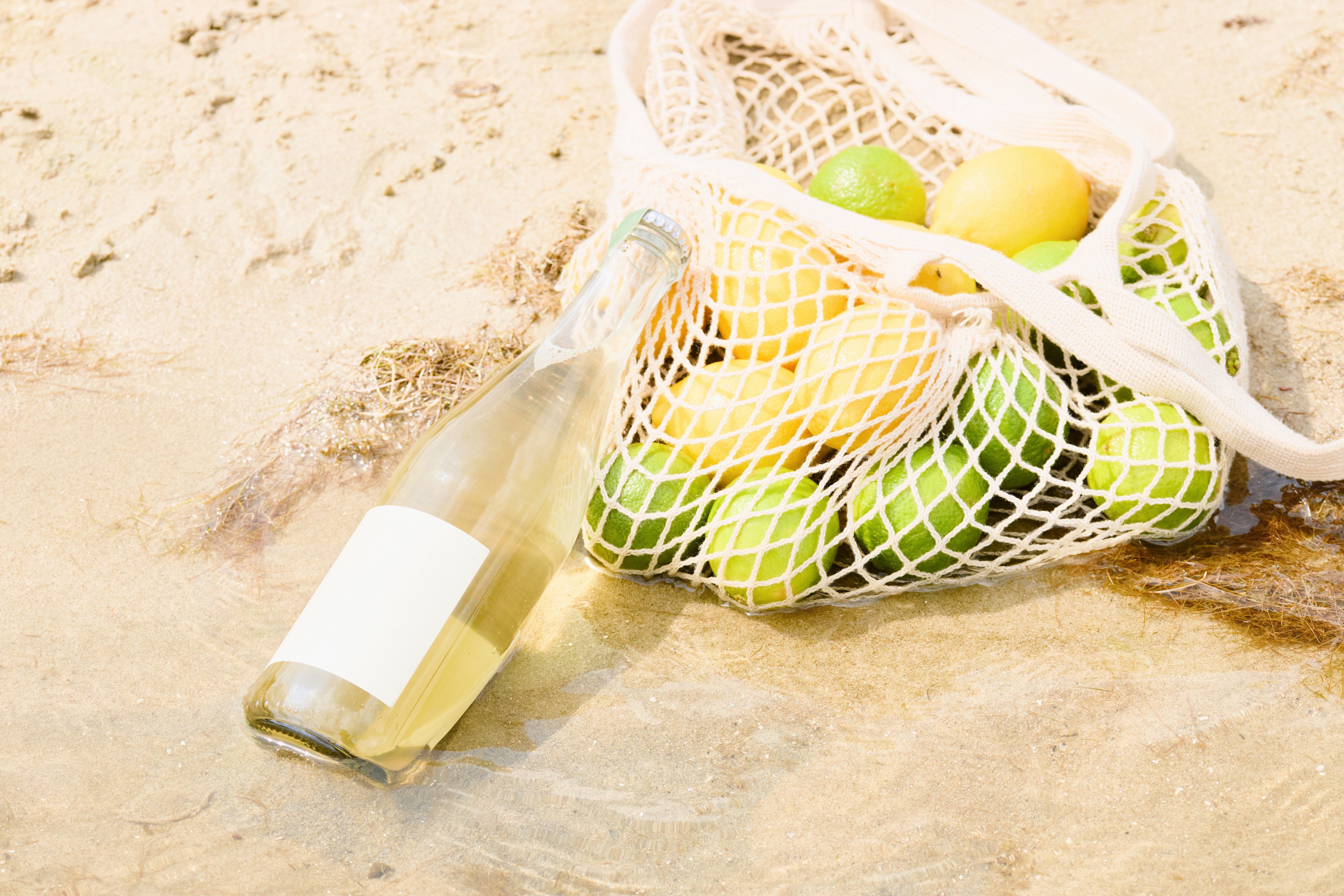 Lemons and a drink on the sand at the beach.