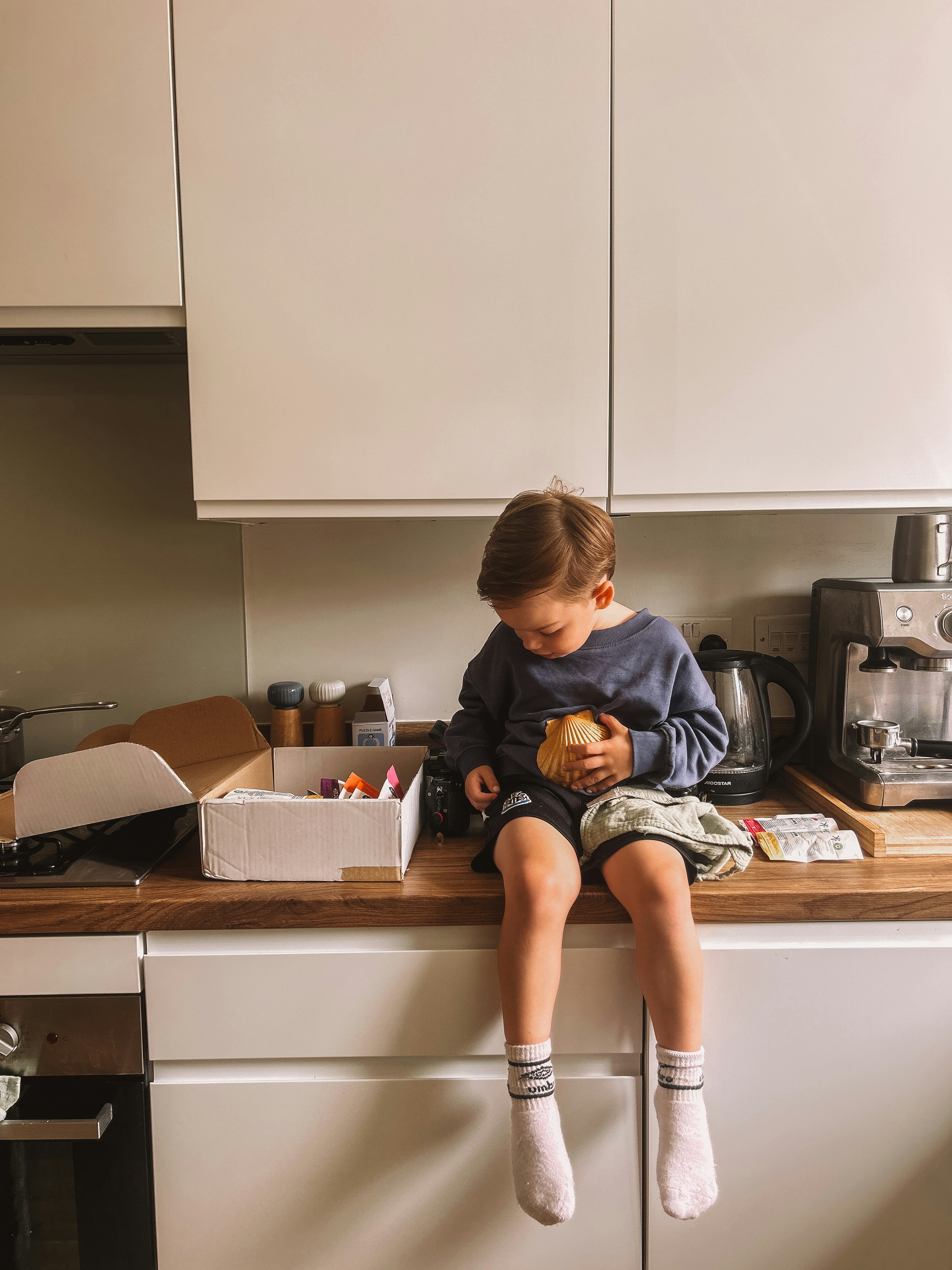 A child sits on the counter in the kitchen.