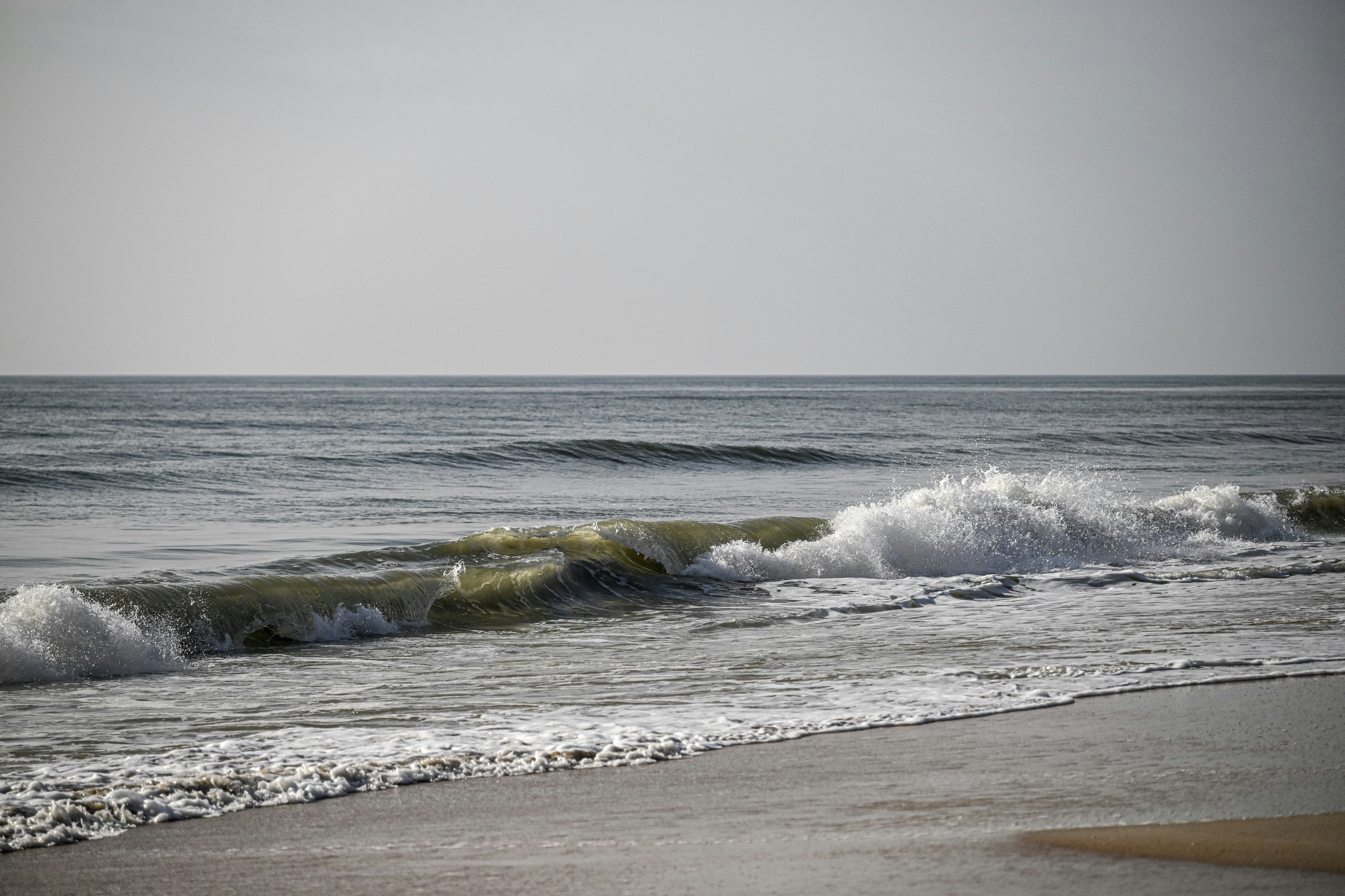 Waves crash onto the shore of a calm sea.