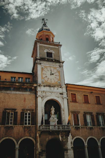 A tall clock tower stands against a cloudy sky.