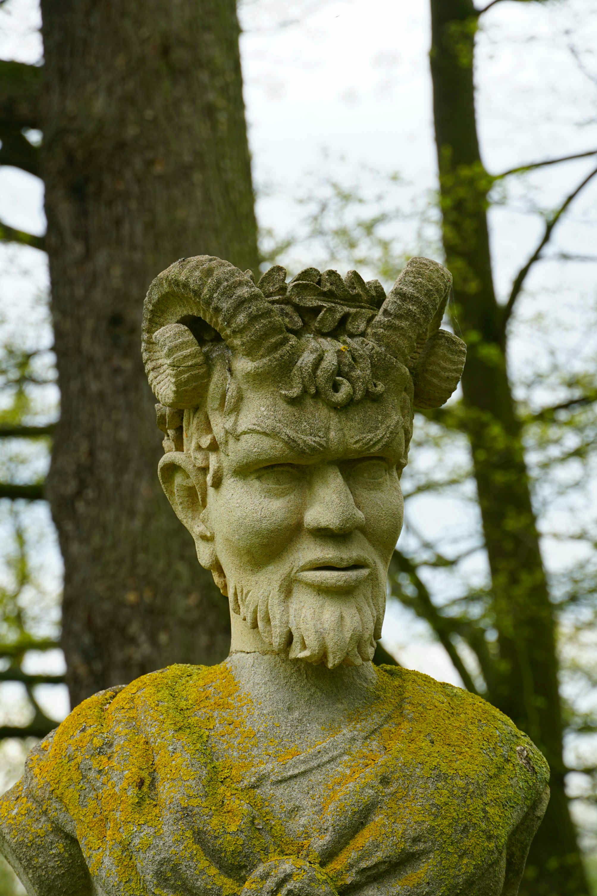 A statue of pan stands amidst nature.