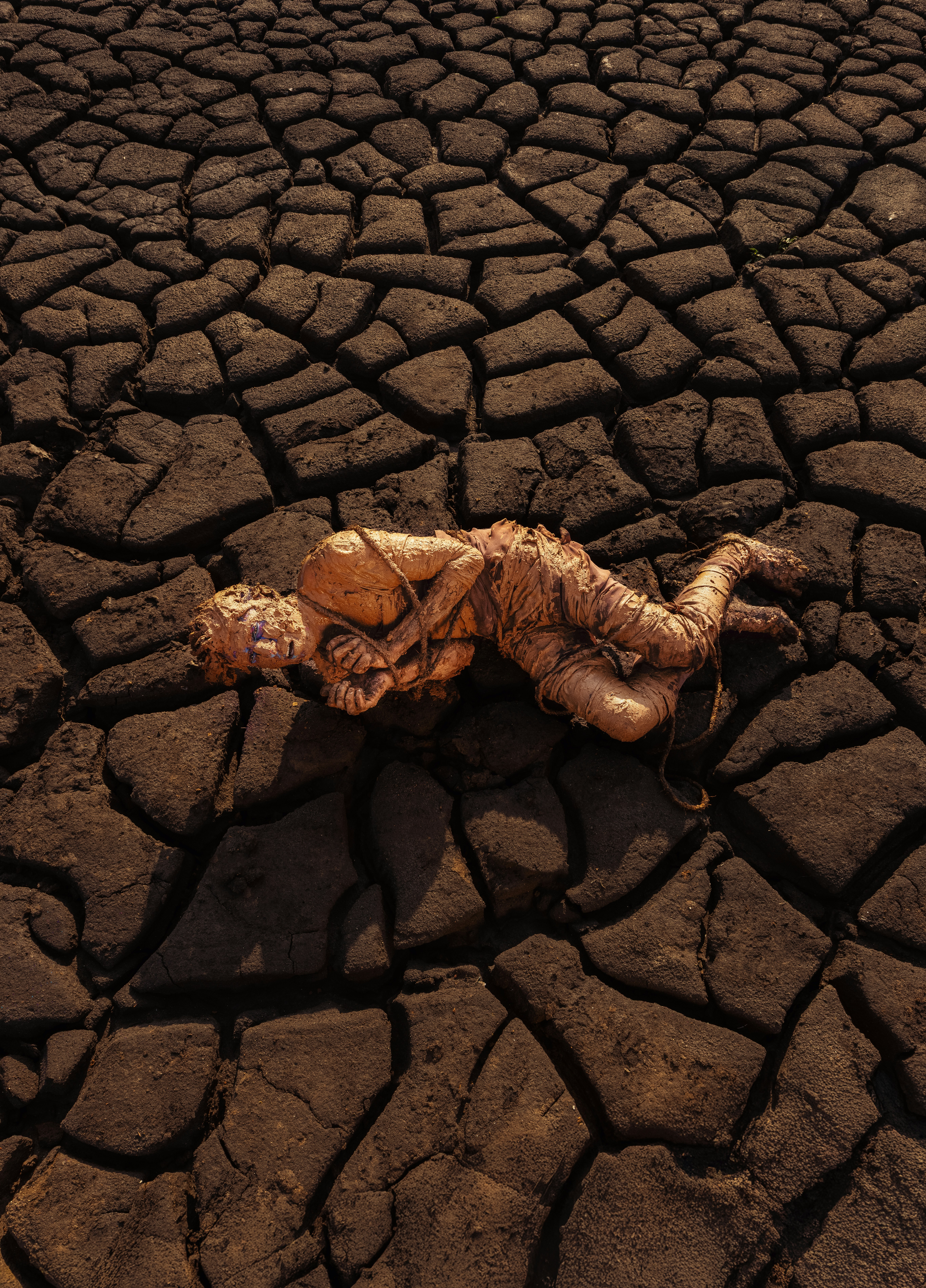 A mummified body lays on cracked earth.