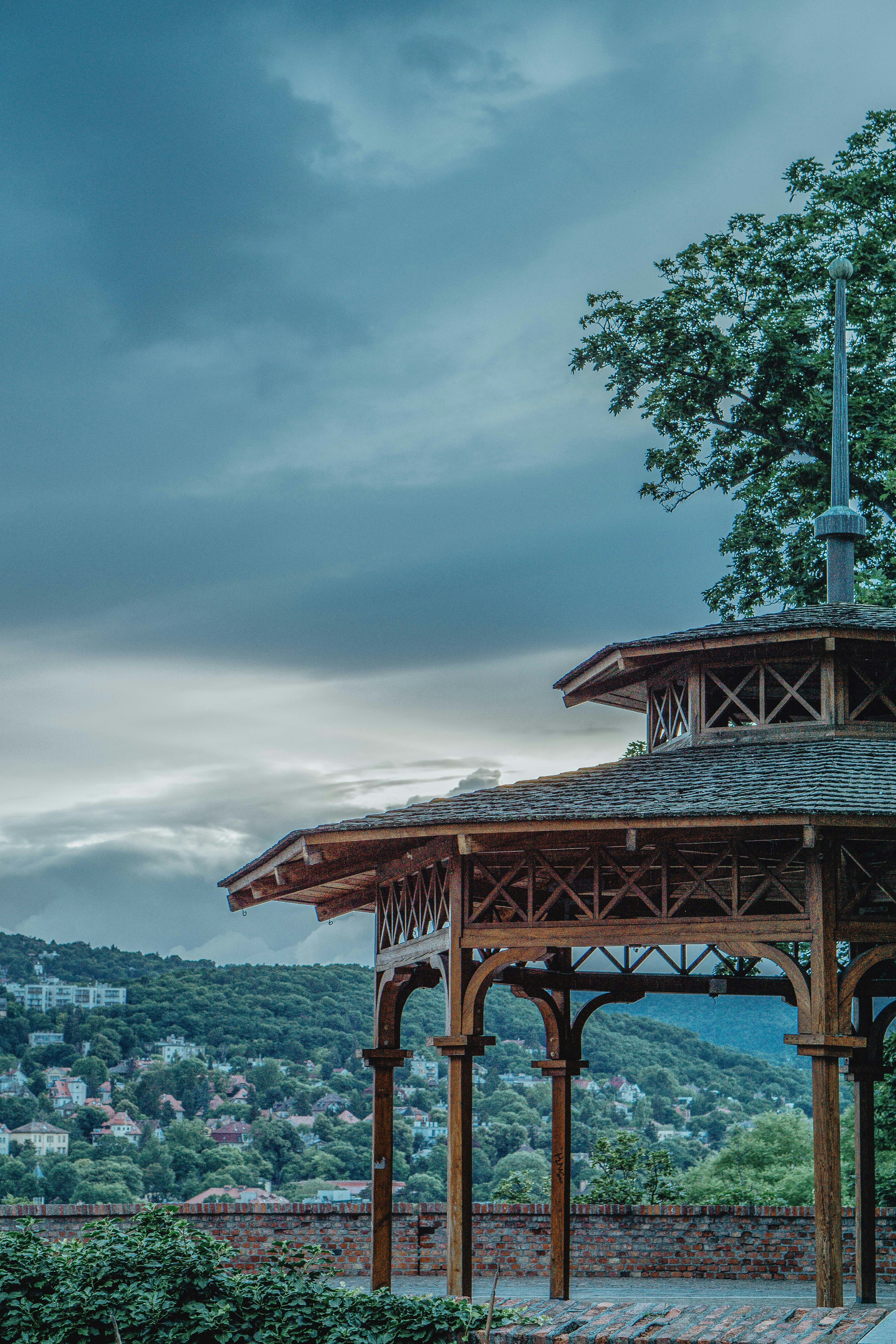 A wooden gazebo overlooks a scenic cityscape.