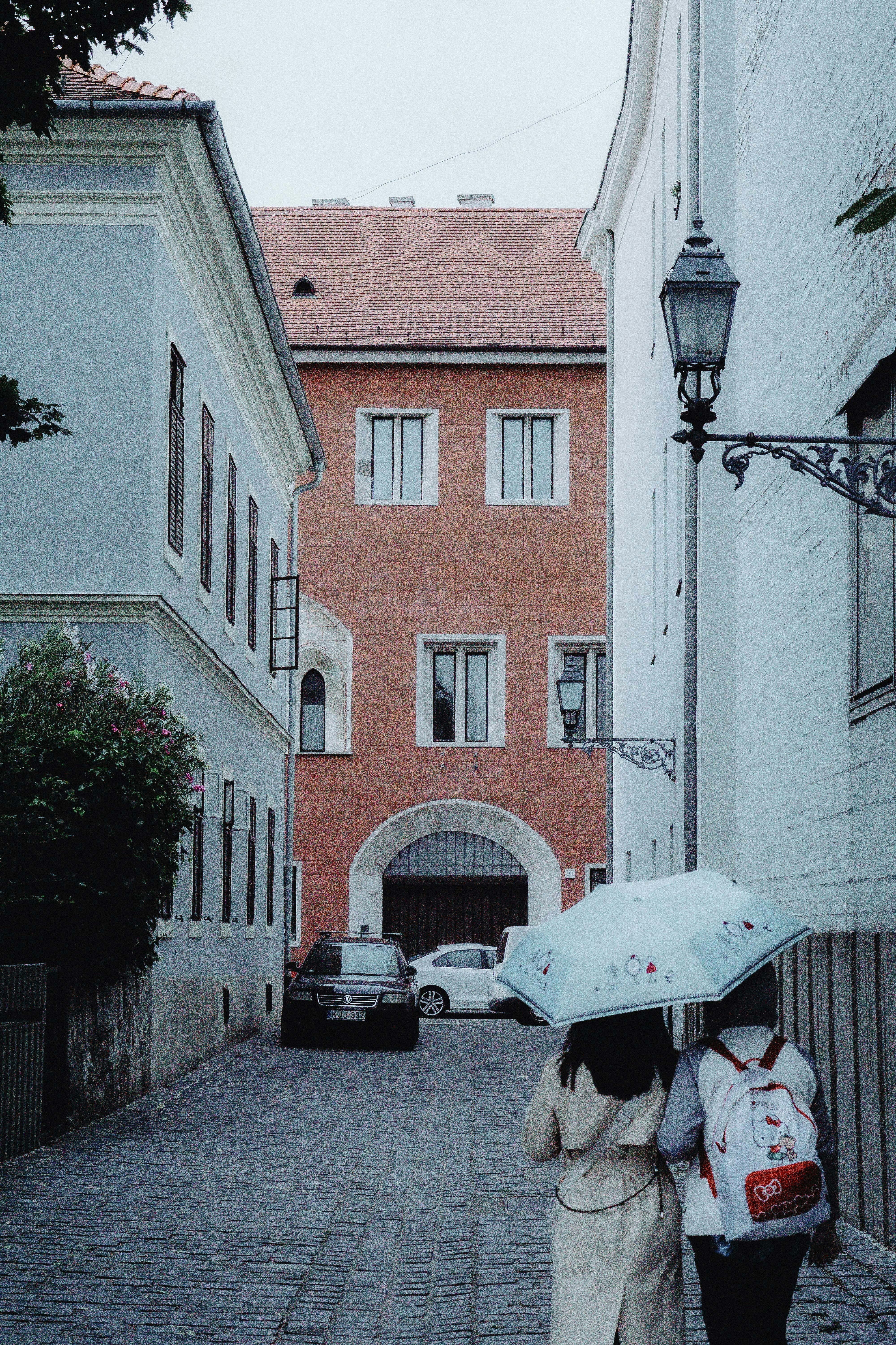 People walk down a european street under an umbrella.