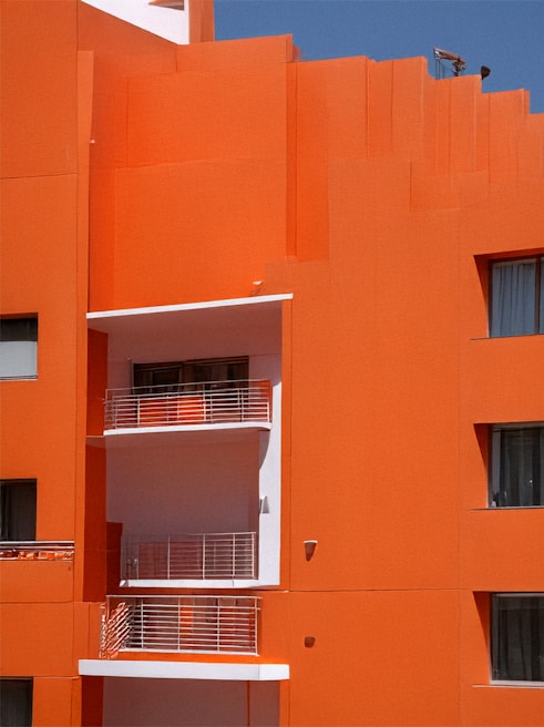 Bright orange building with white balconies and windows.