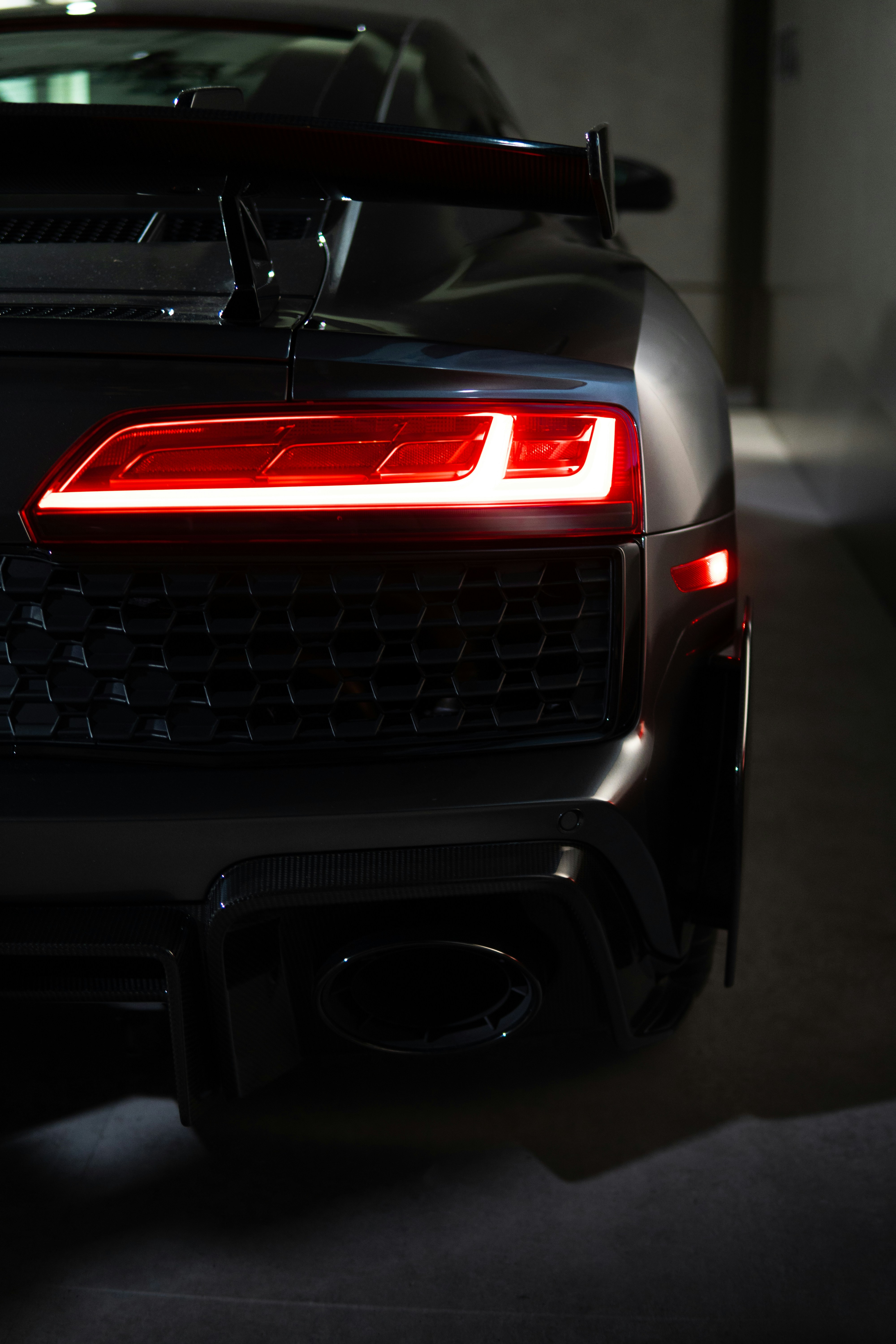 A sleek black sports car's taillights are lit.