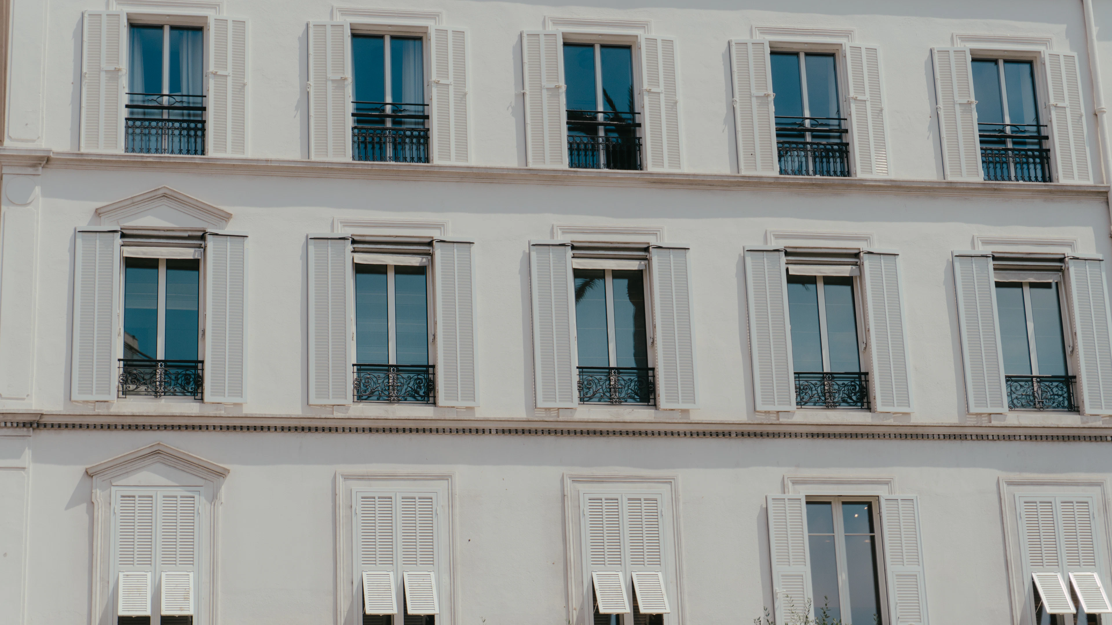 Hotel facade with tall windows and red shutters