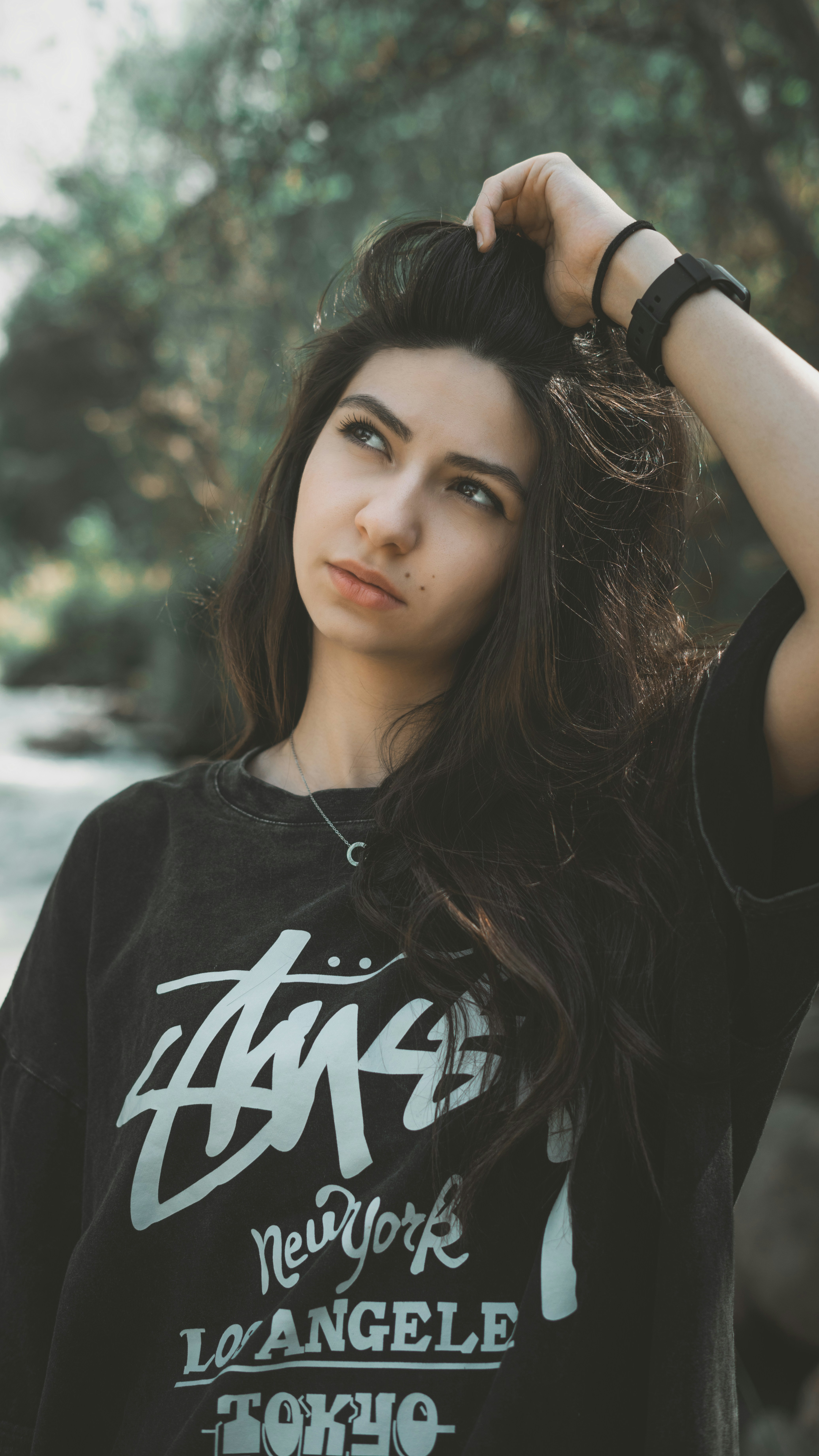 髪を触りながらポーズをとる女性。