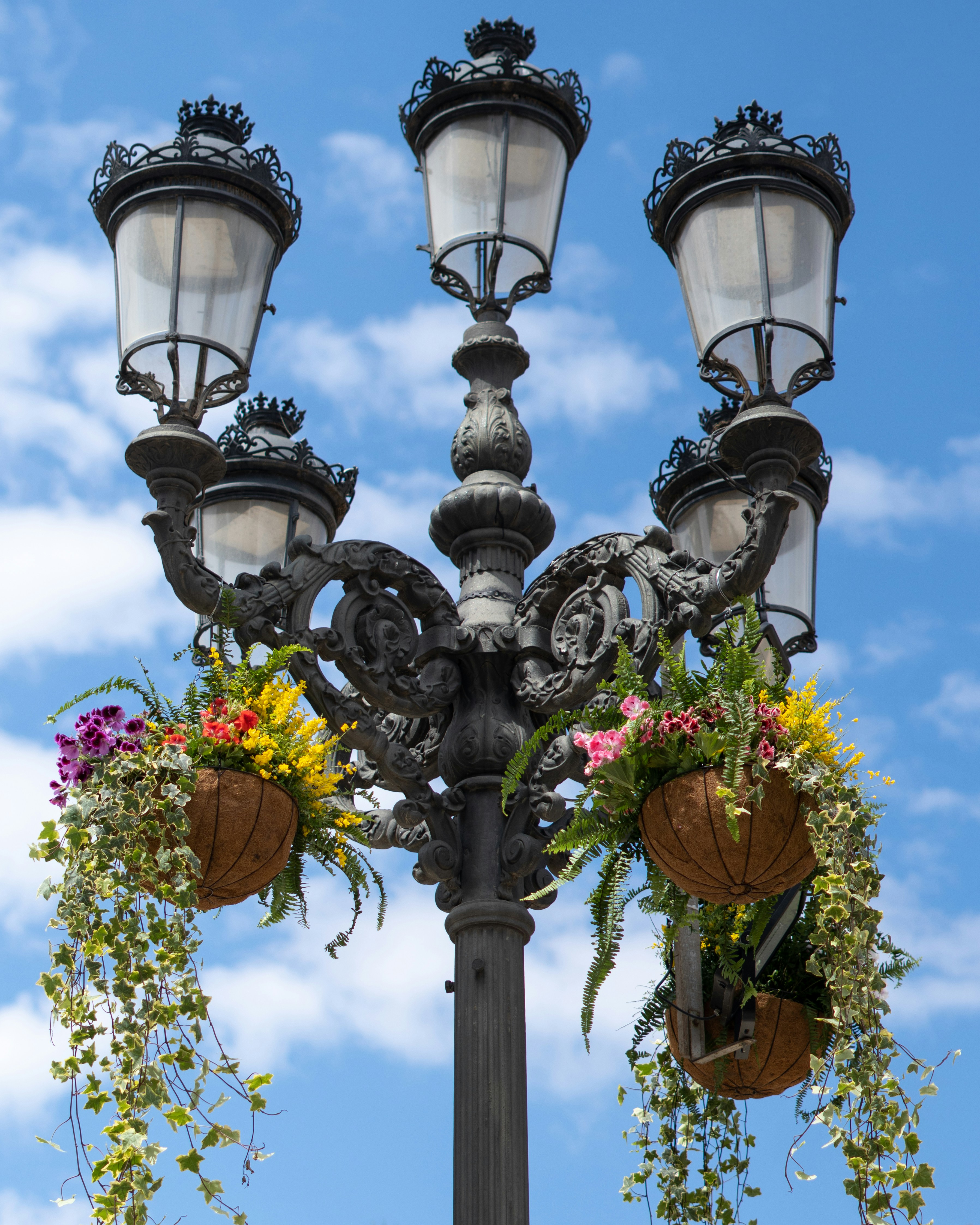 Ornate lamppost adorned with hanging flower baskets.
