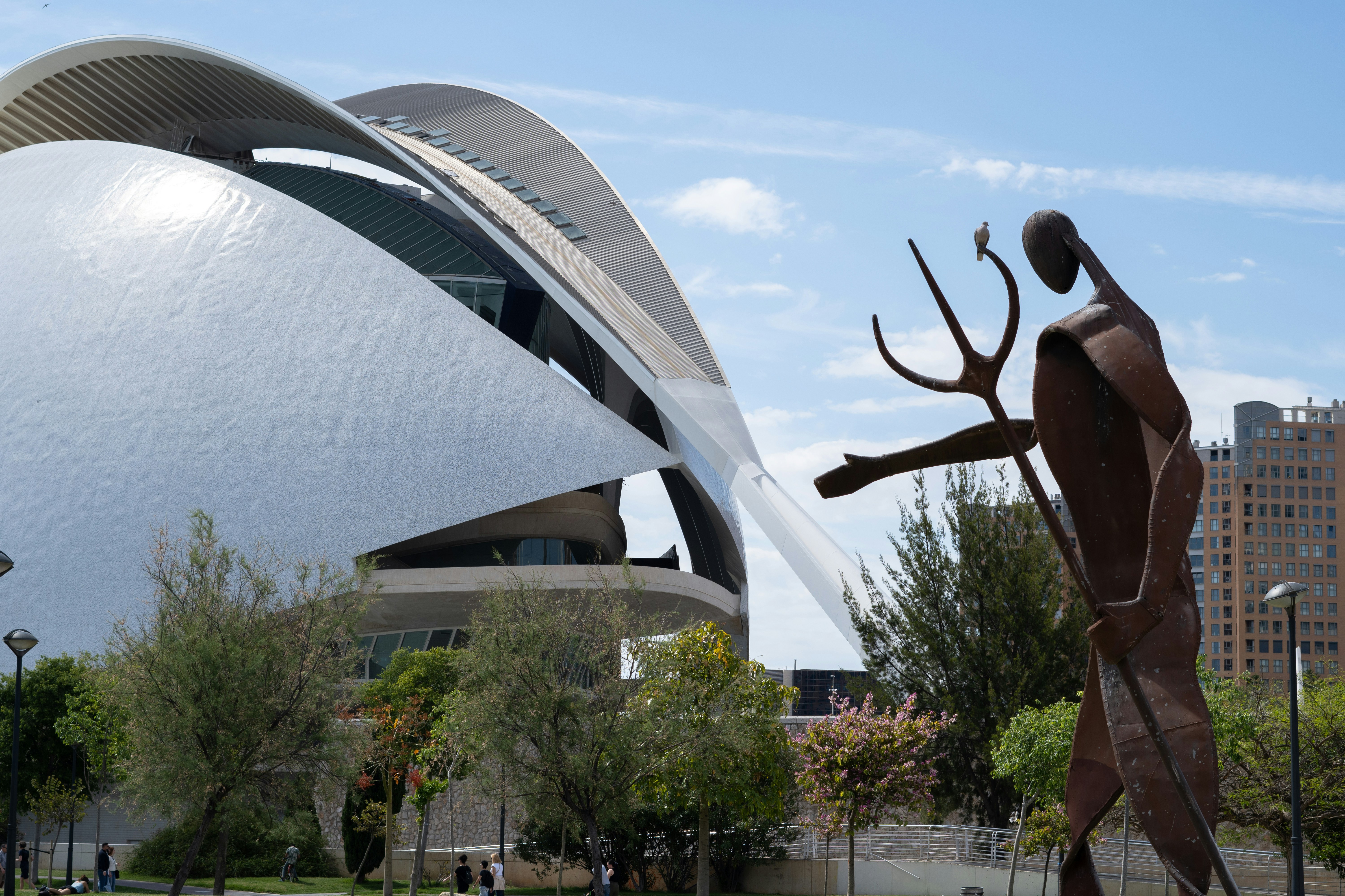Sculpture stands near a modern, white building.