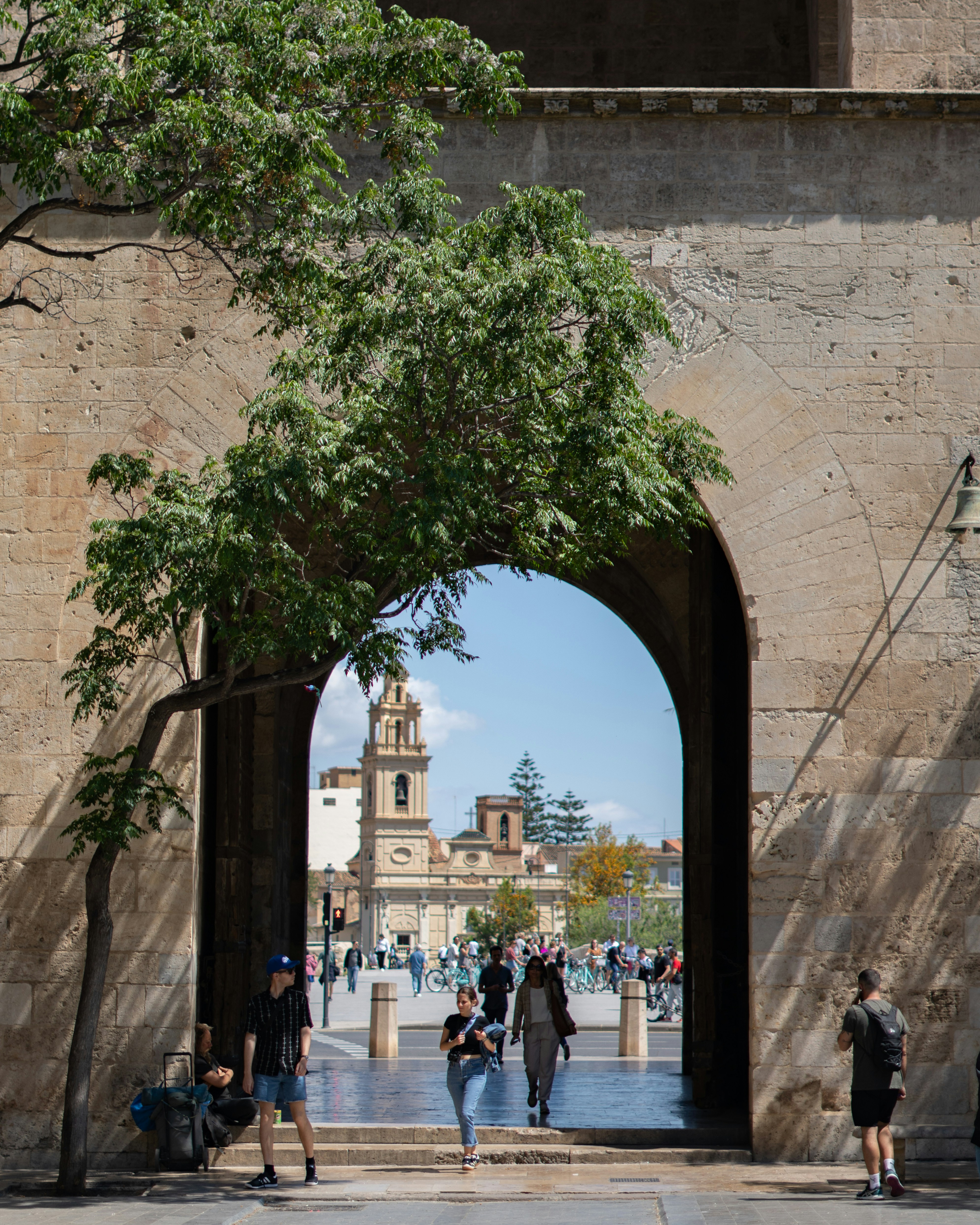 People walk through an archway toward a building.