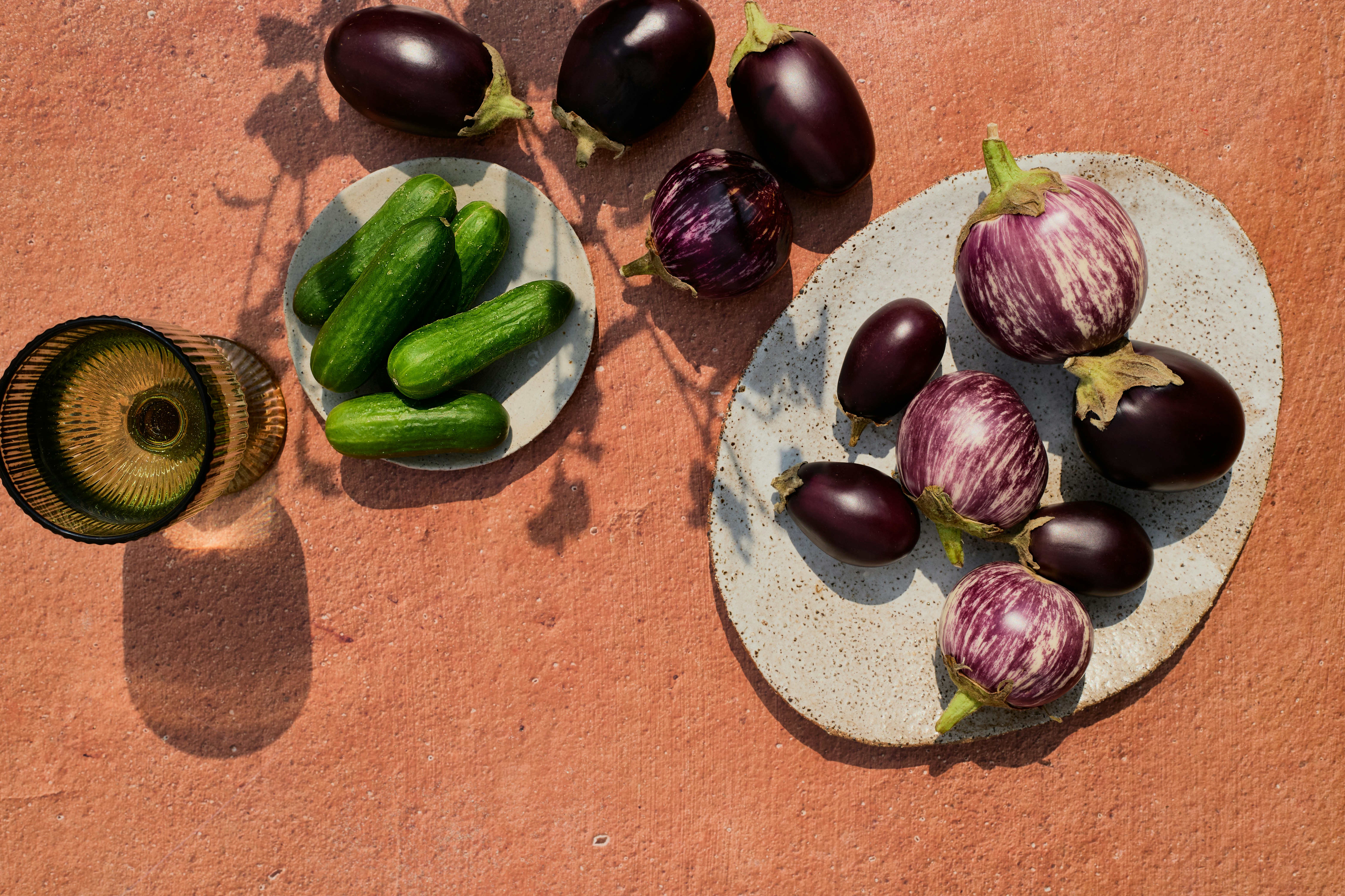 Eggplants and cucumbers are arranged artistically on a surface.