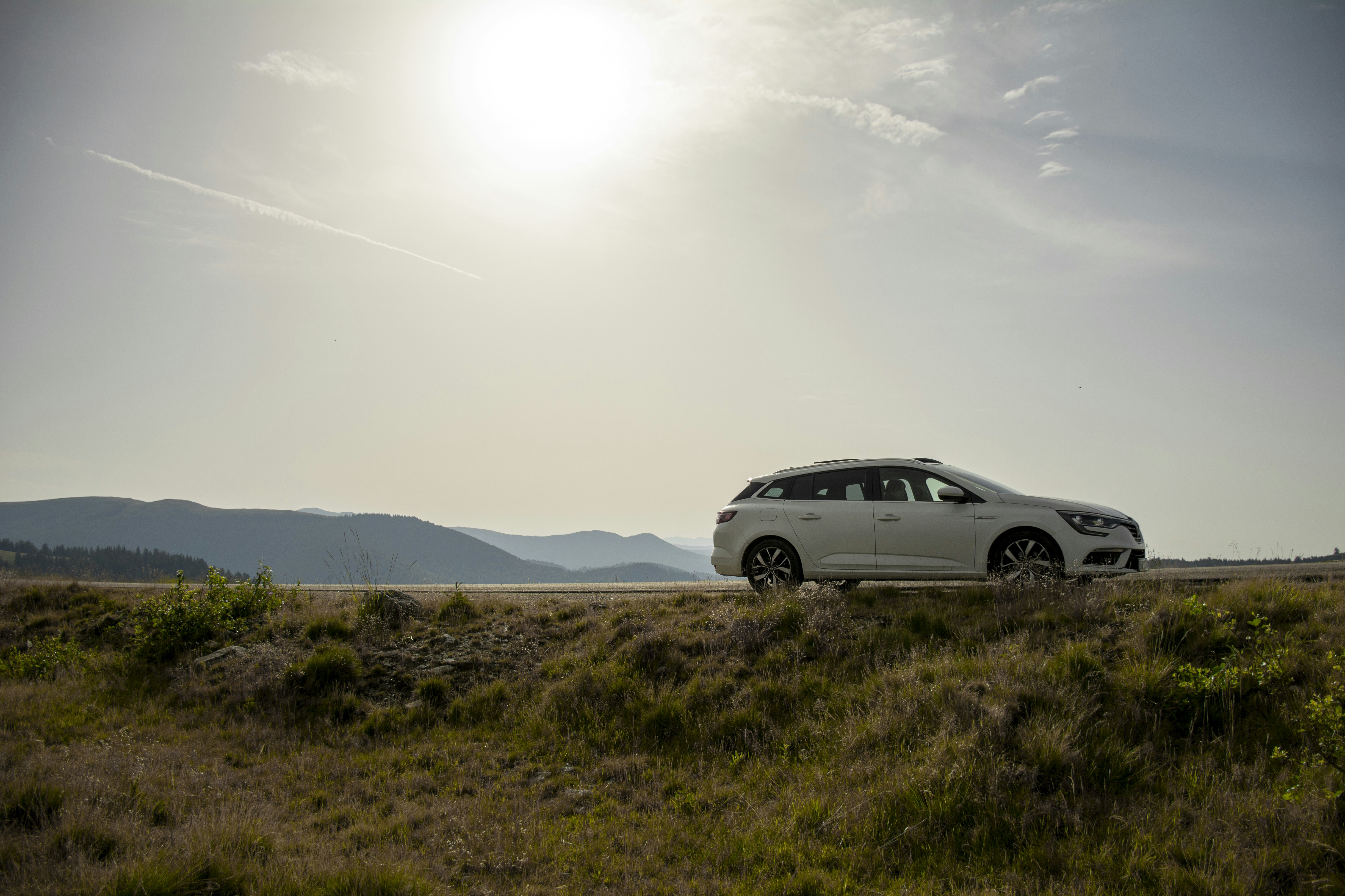 A white car drives along a road.