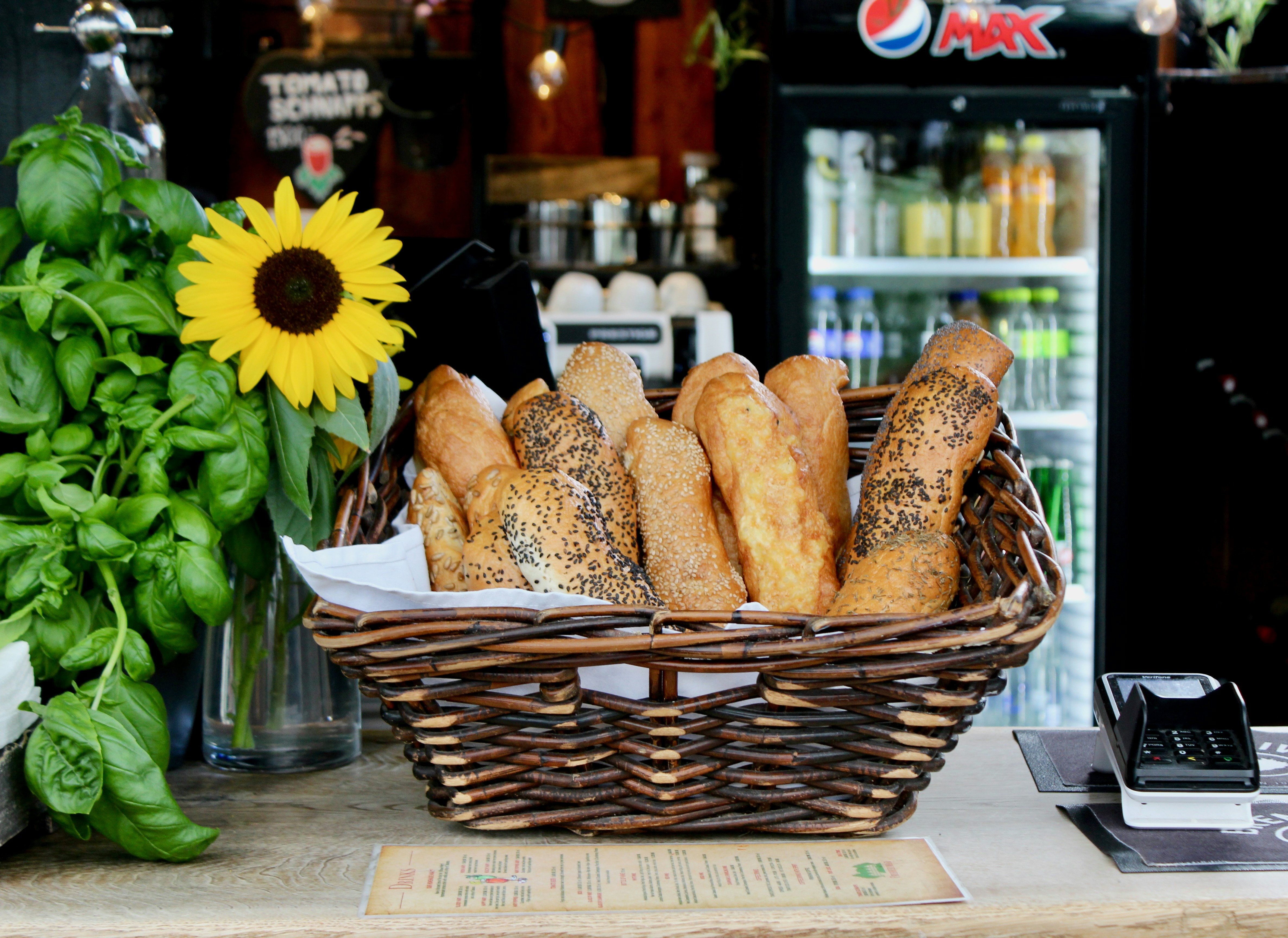 Bread basket and sunflower on a restaurant counter.