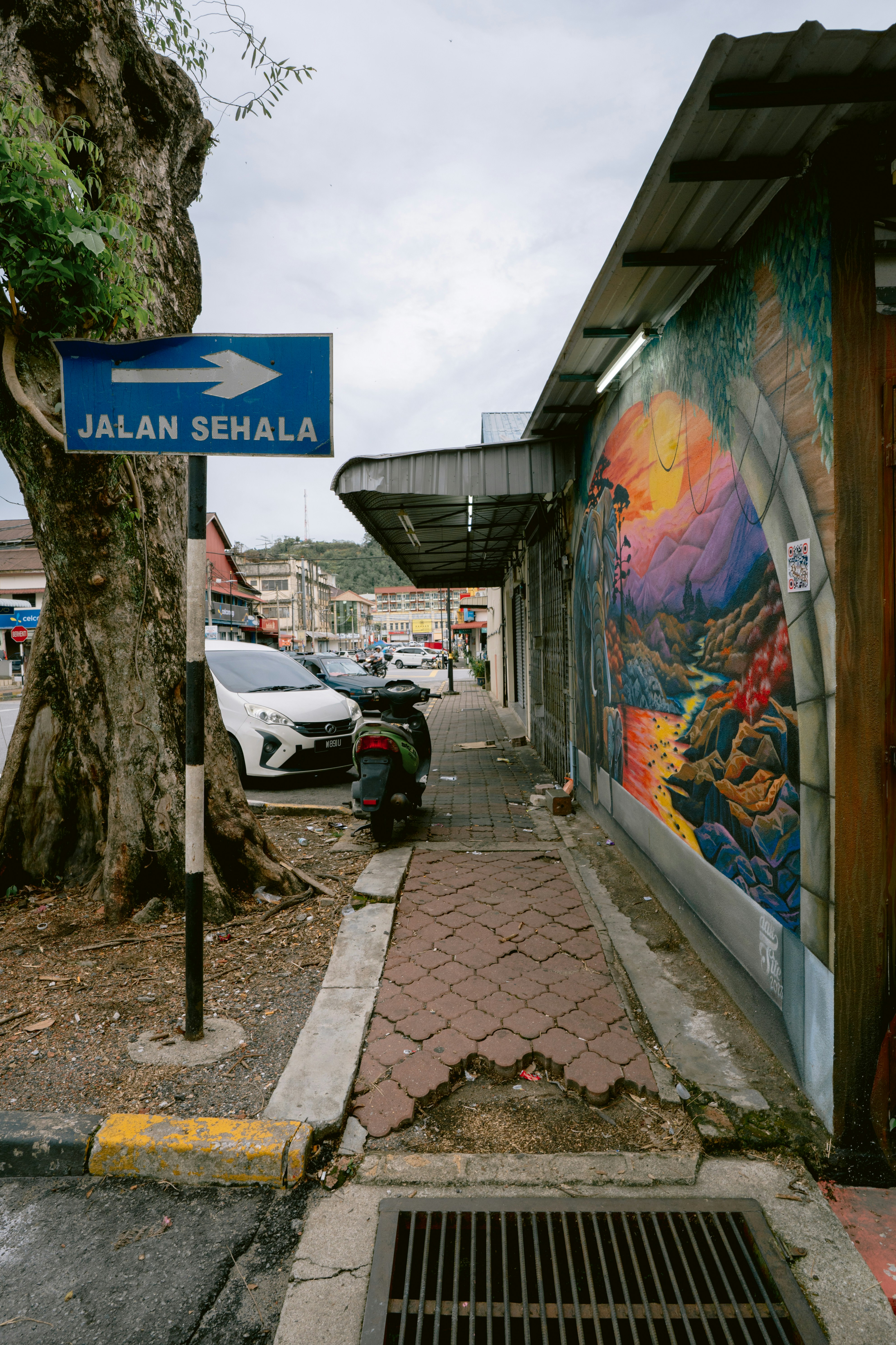 A sidewalk with a mural and street sign.