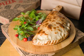 A delicious calzone sits on a wooden board.