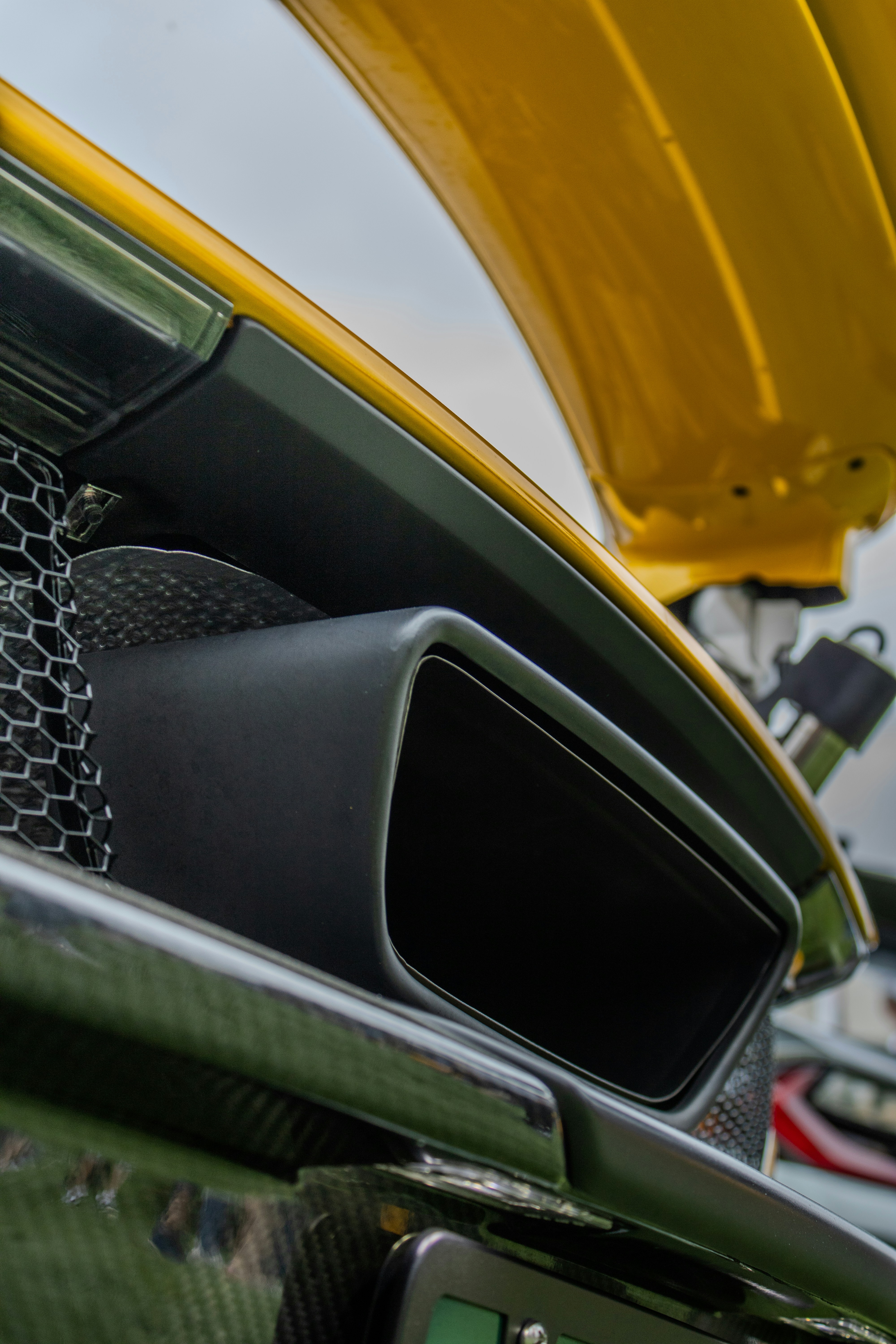 Hier ist eine Bildunterschrift für das Bild: der Lüftungsschlitz des Autos, mit gelber Motorhaube im Hintergrund.