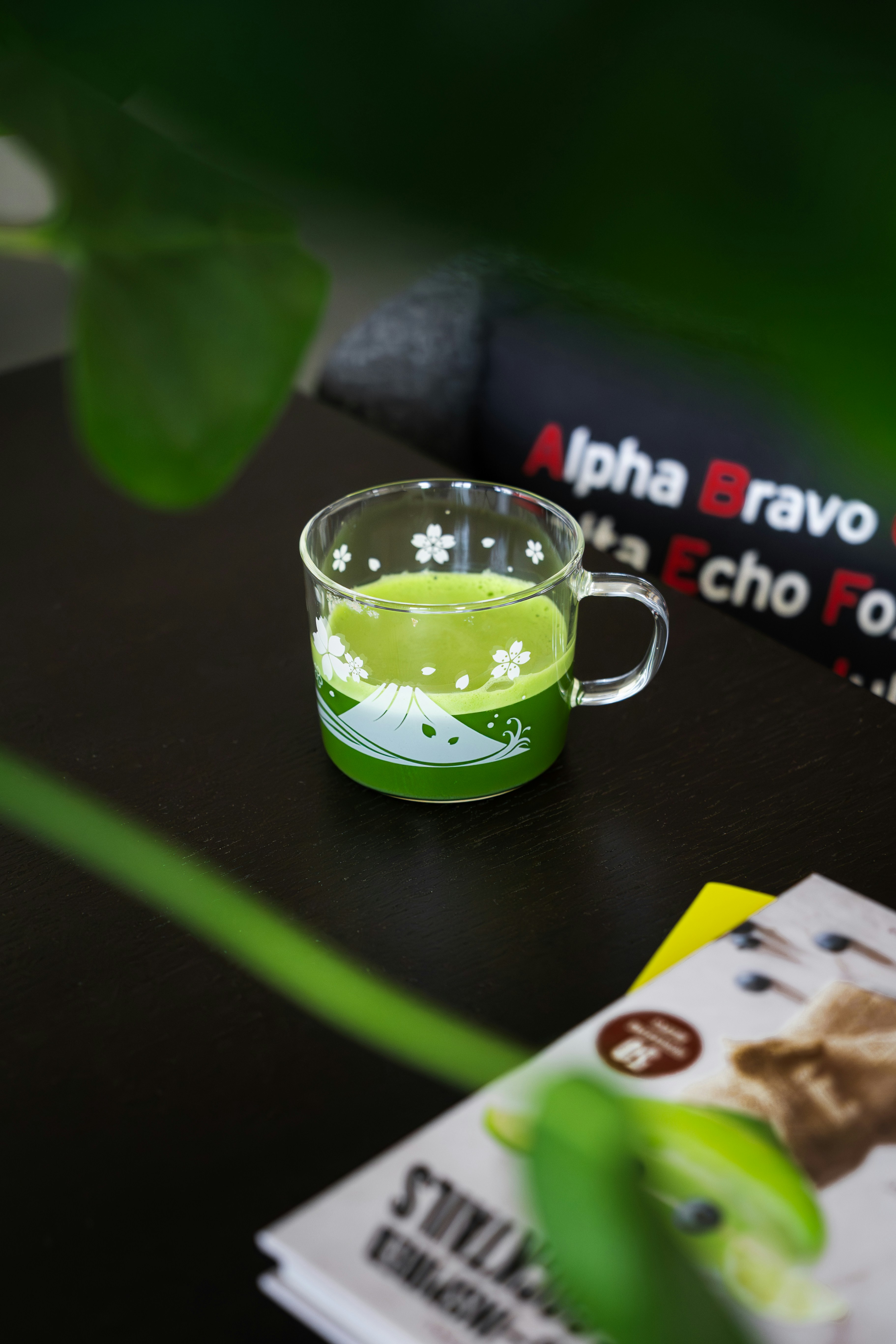 Matcha tea rests on a dark surface near a book.