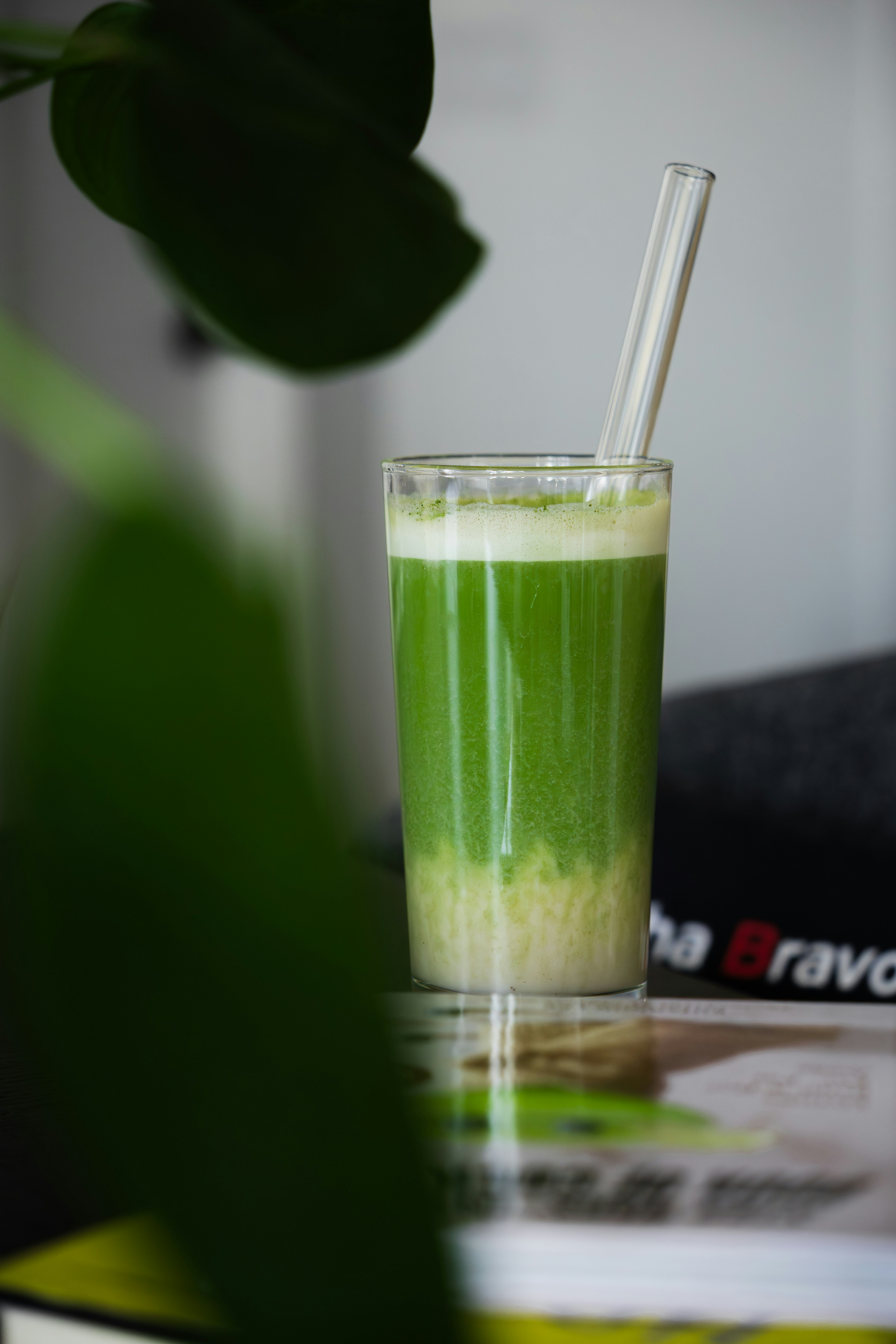 Here's a caption for the image: green juice with a glass straw.