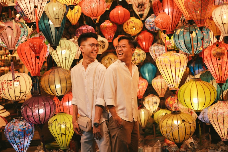 Two men pose amongst colorful lanterns.