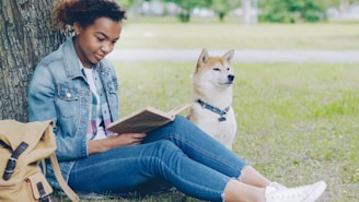 Woman reads a book with her dog in the park.