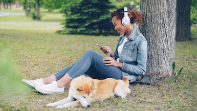 Woman enjoys music in the park with her dog.