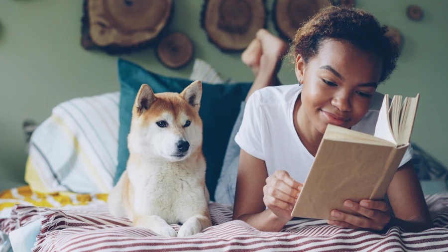 Nia reading a book on the bed while Miso rests beside her