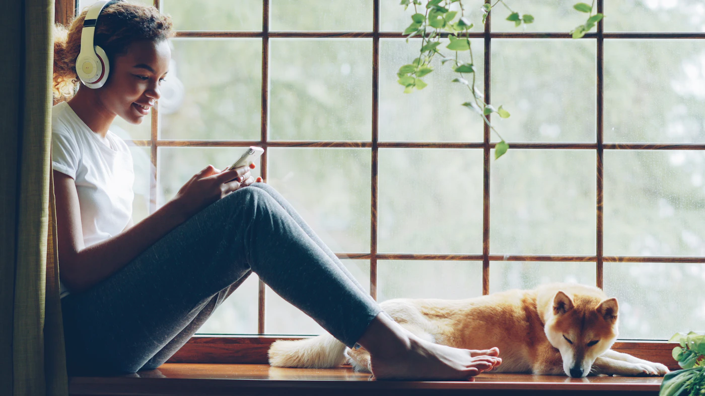Mujer descansando con su perro junto a una ventana doméstica
