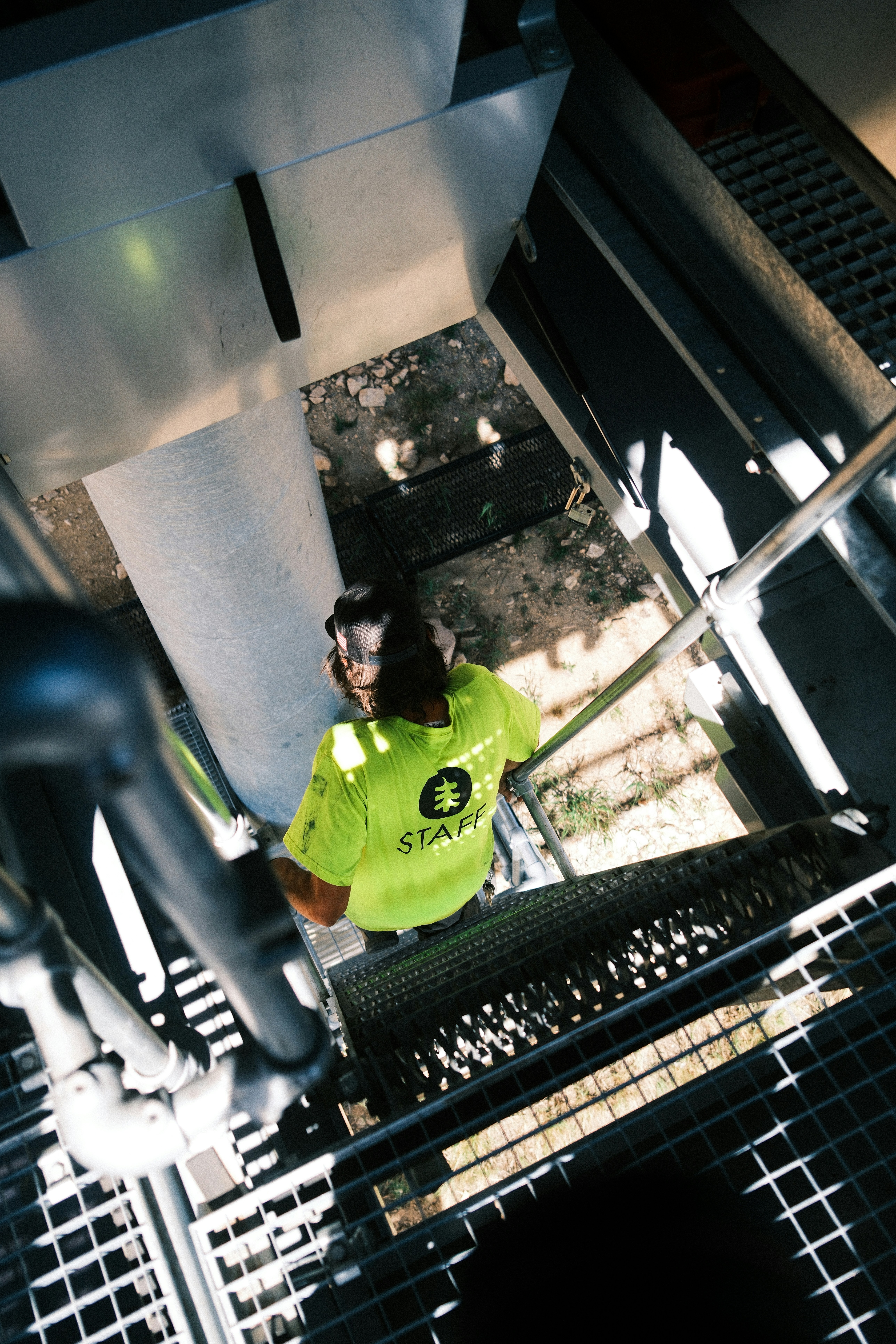 A worker in a green shirt climbs stairs.