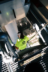 A worker in a green shirt climbs stairs.