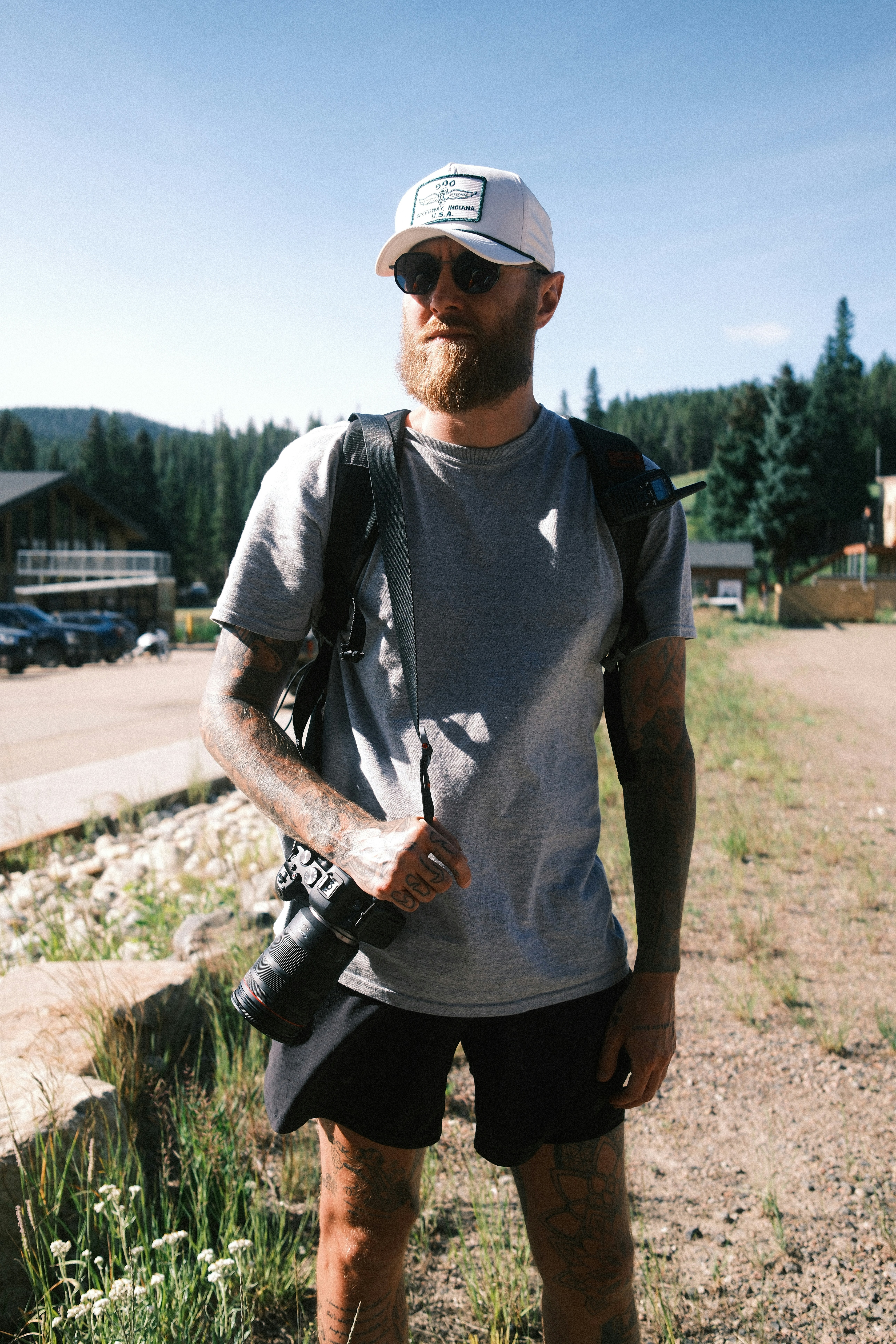 Man poses outside with camera in a beautiful environment.