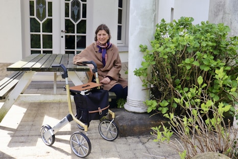 Woman poses with a rollator outside a building.