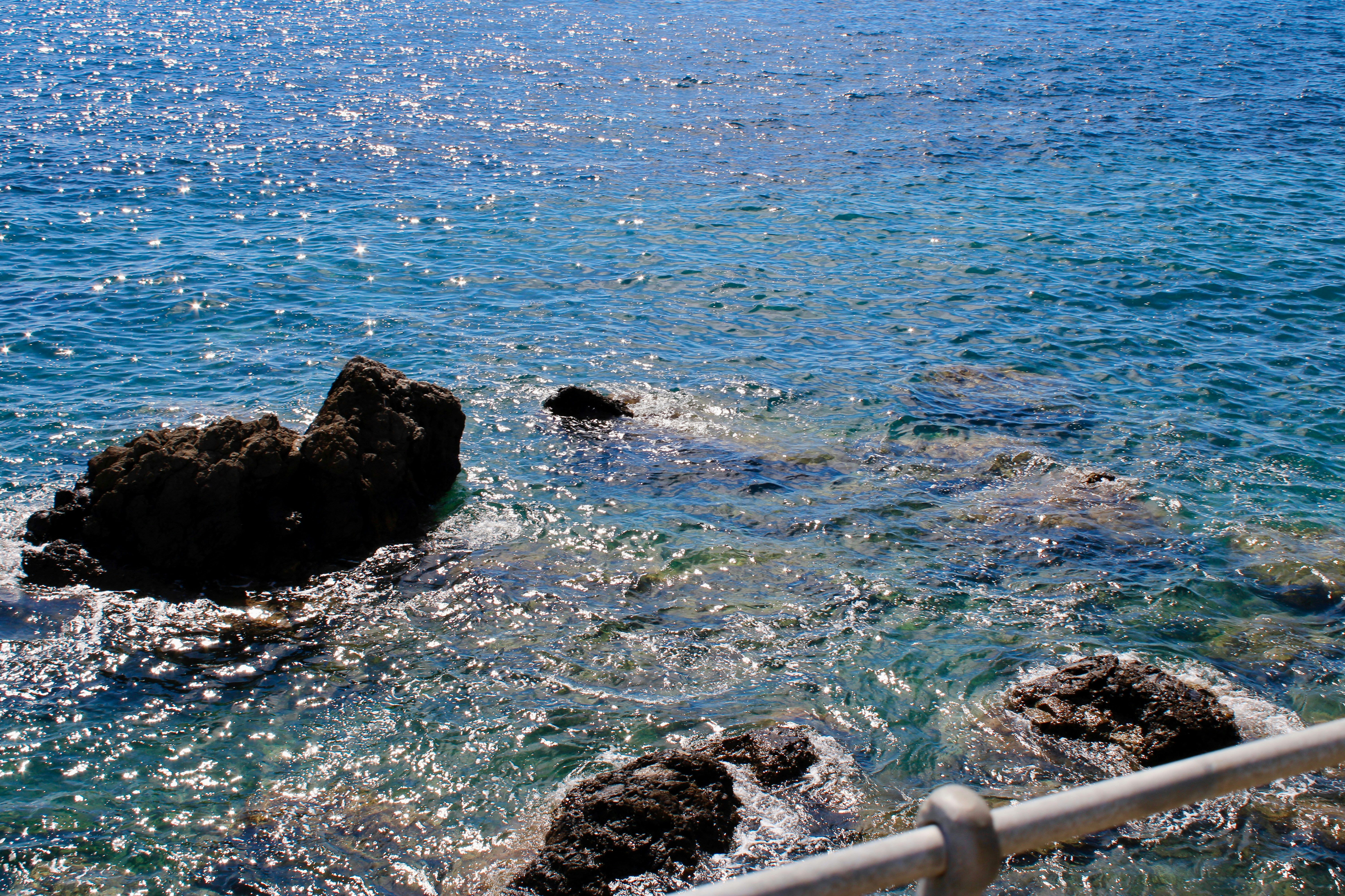 Rocks emerge from the sparkling blue ocean water.