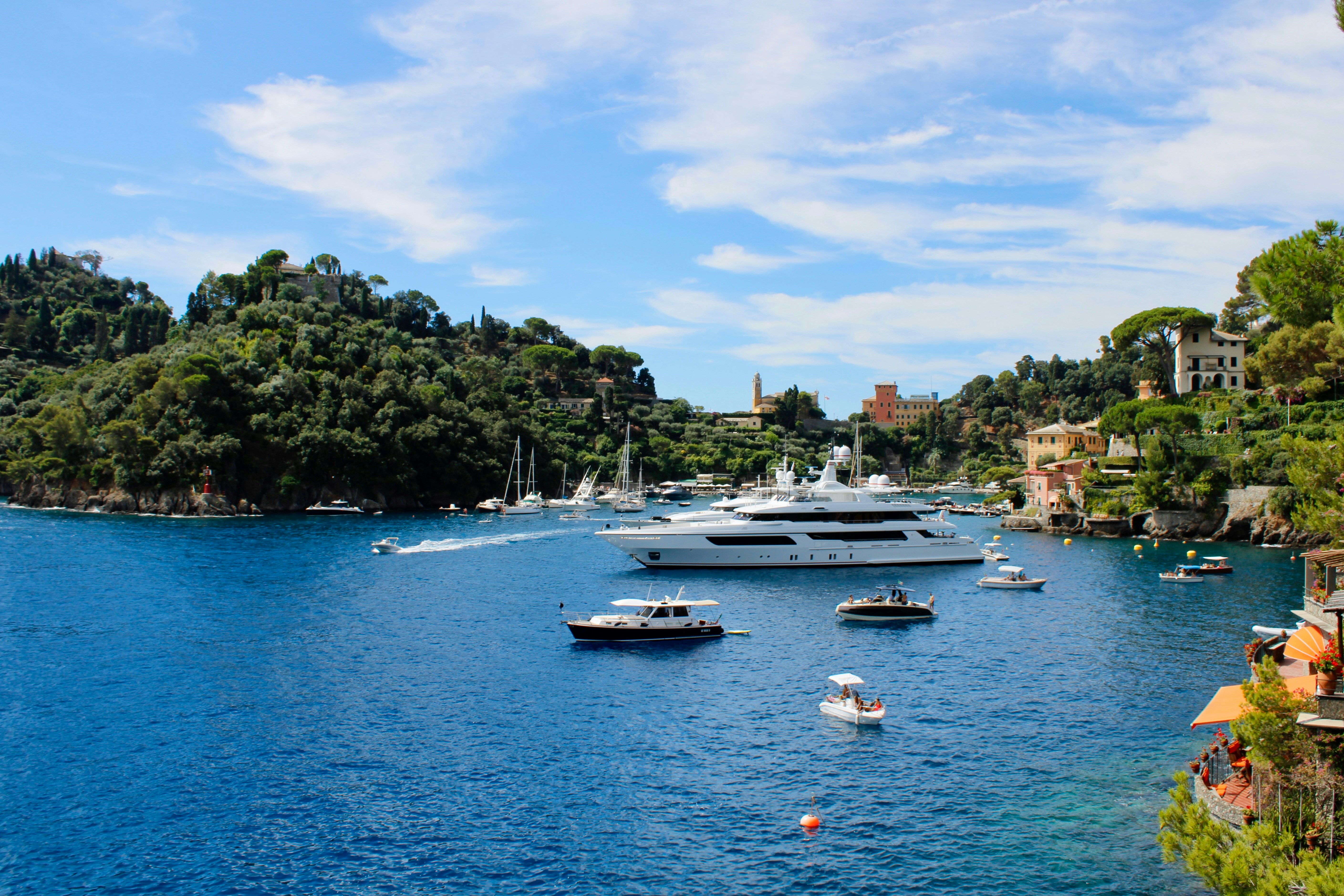 Beautiful yachts are anchored in a clear, blue bay.