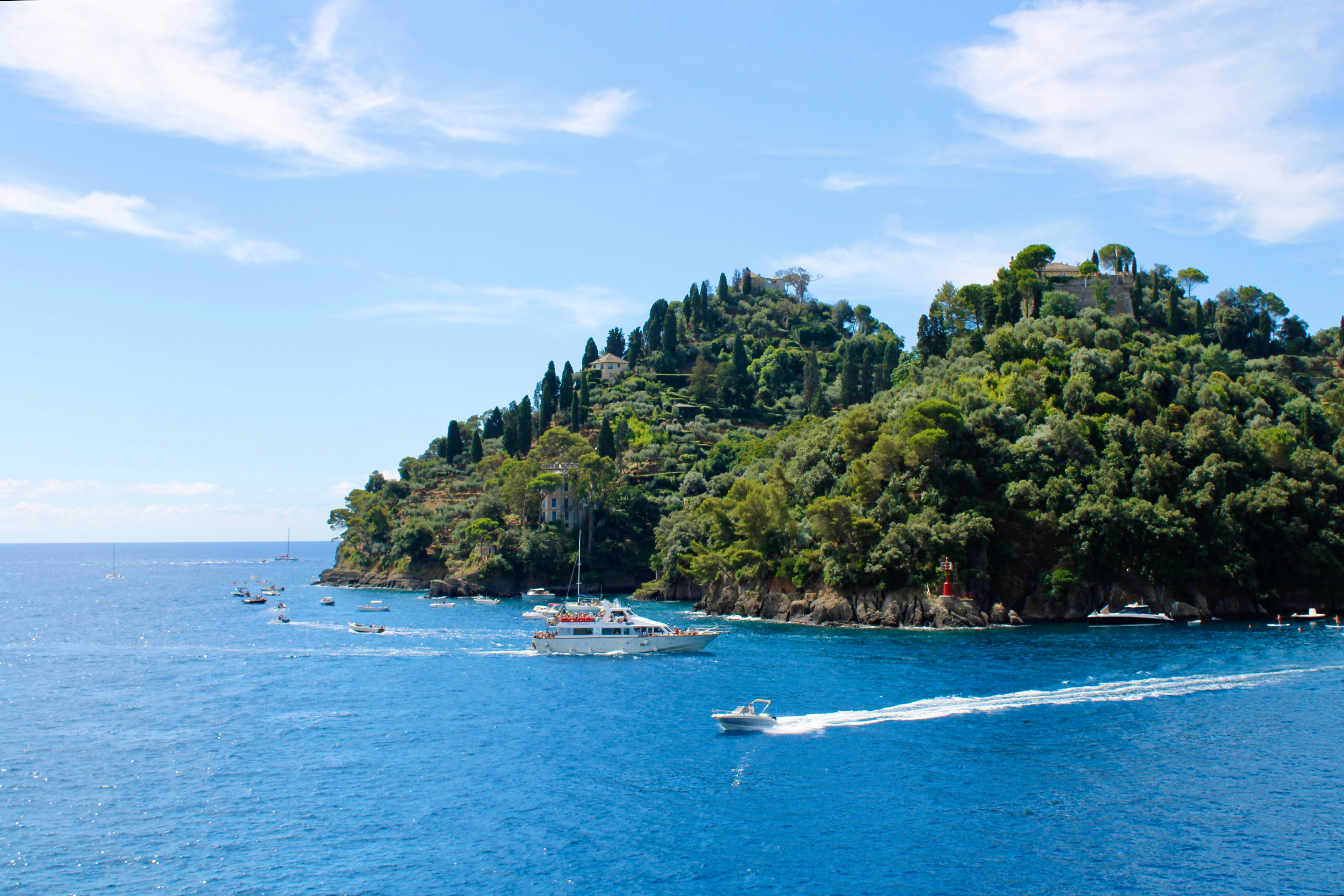 Boats cruise near a lush, green island.