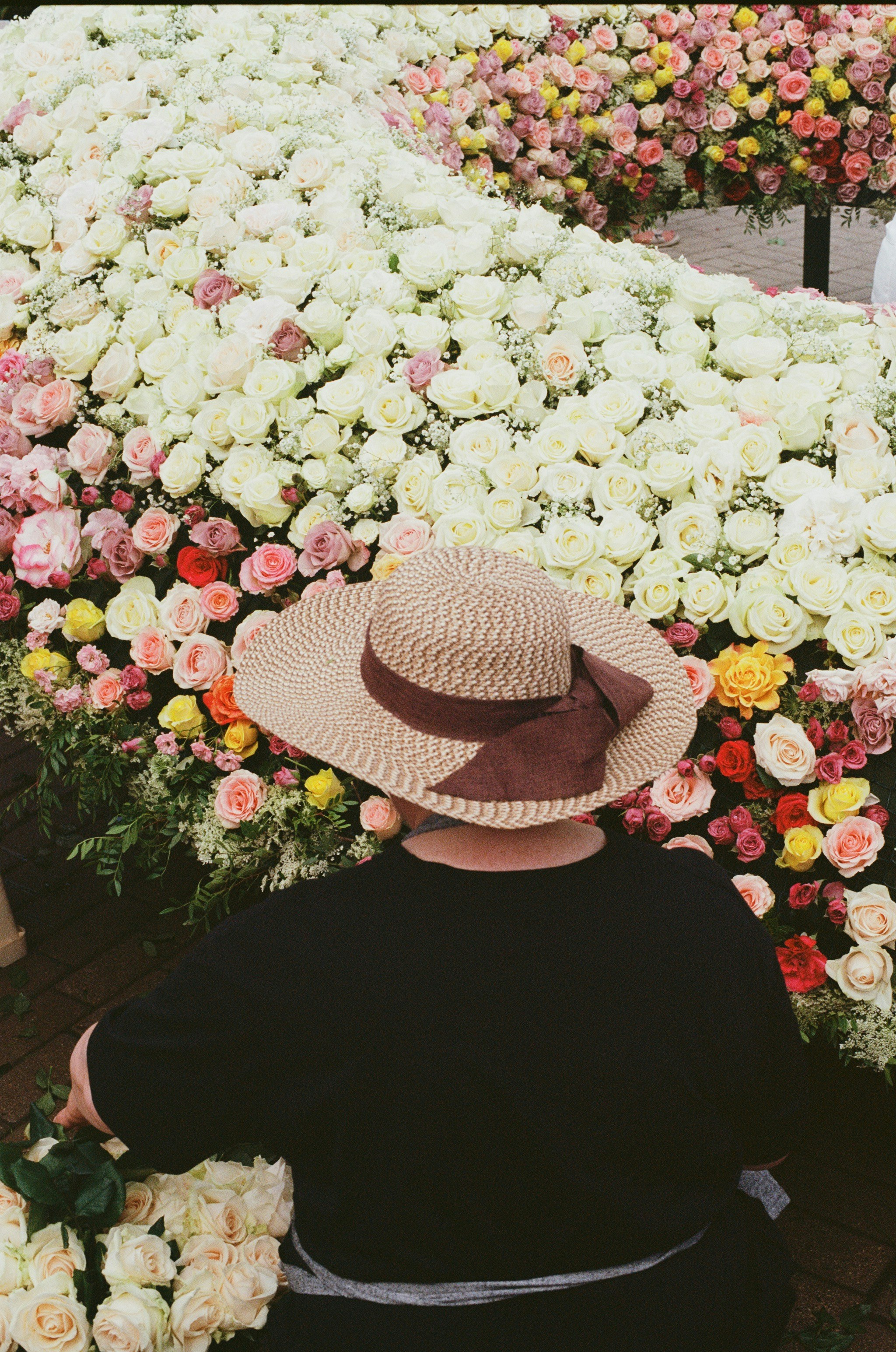 Woman in hat admires a large flower arrangement