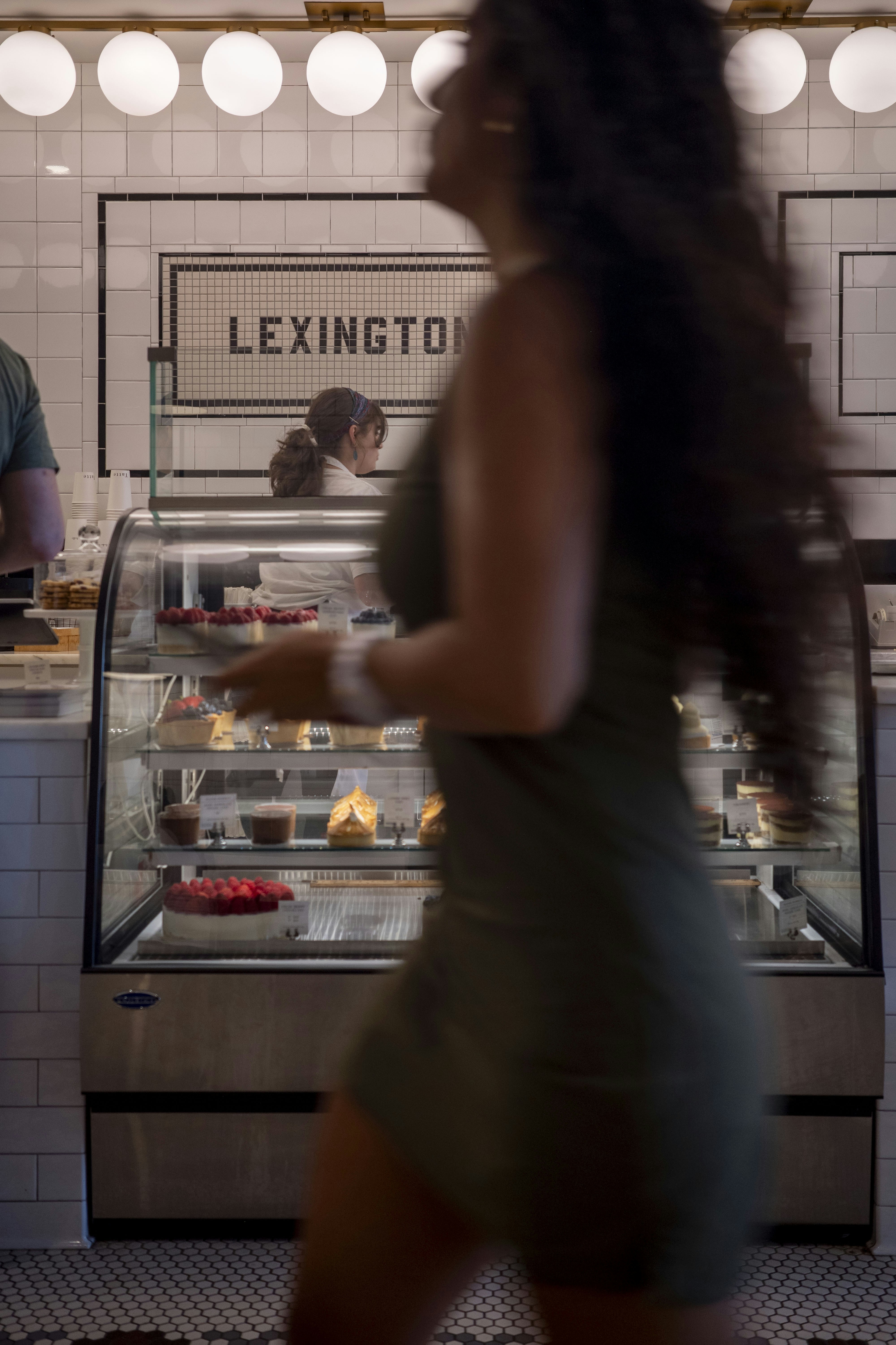 Woman walks past a bakery display.