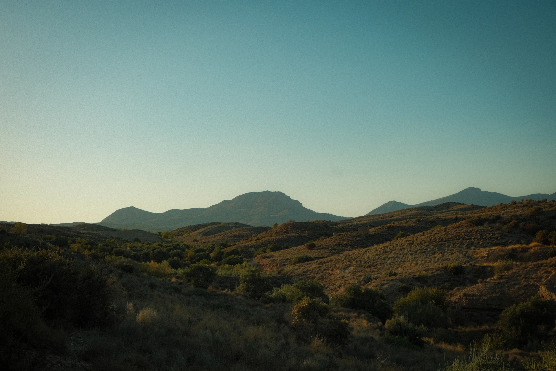 Hills and mountains under a clear, blue sky.