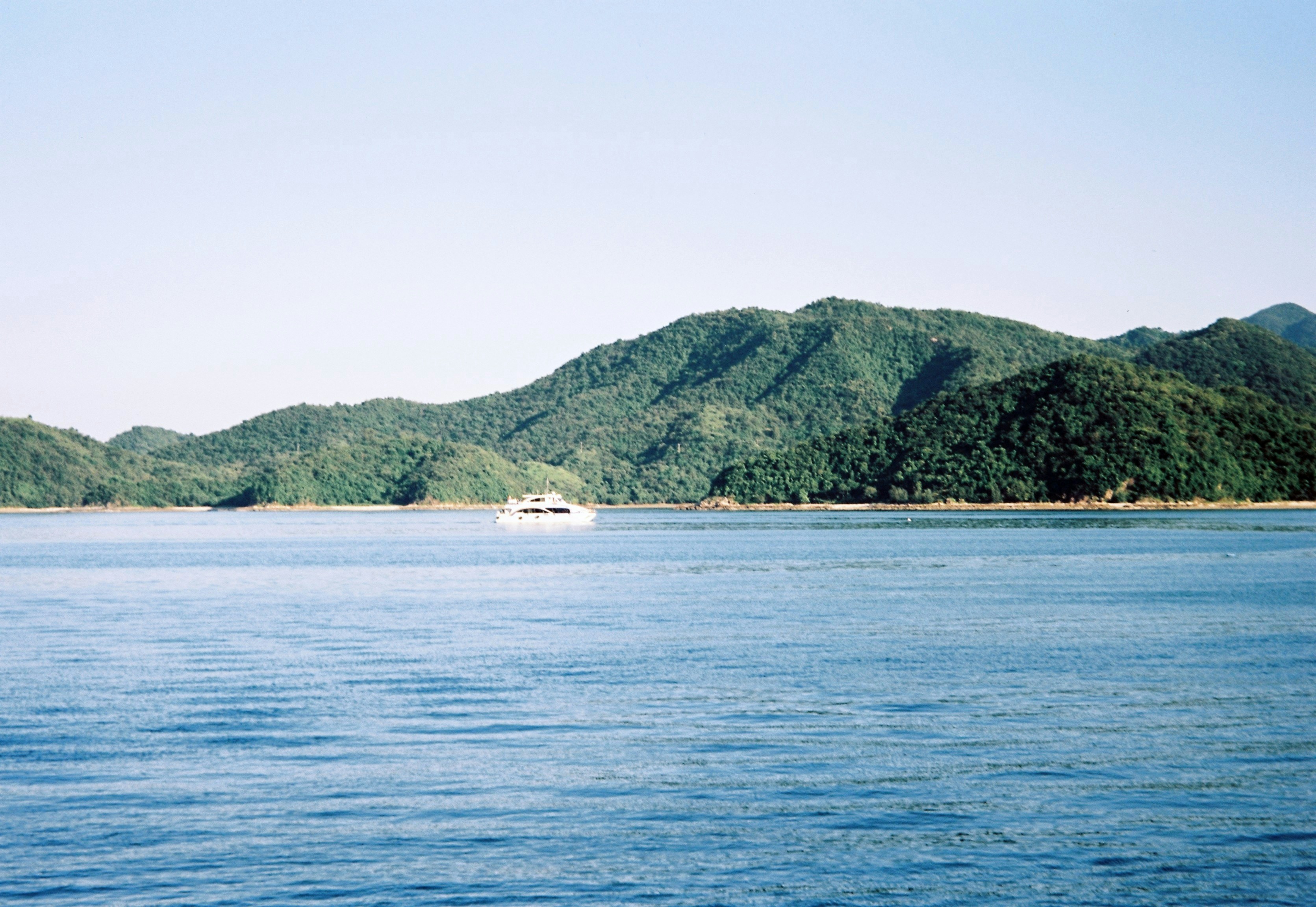 Boat sailing on the sea near a green island.