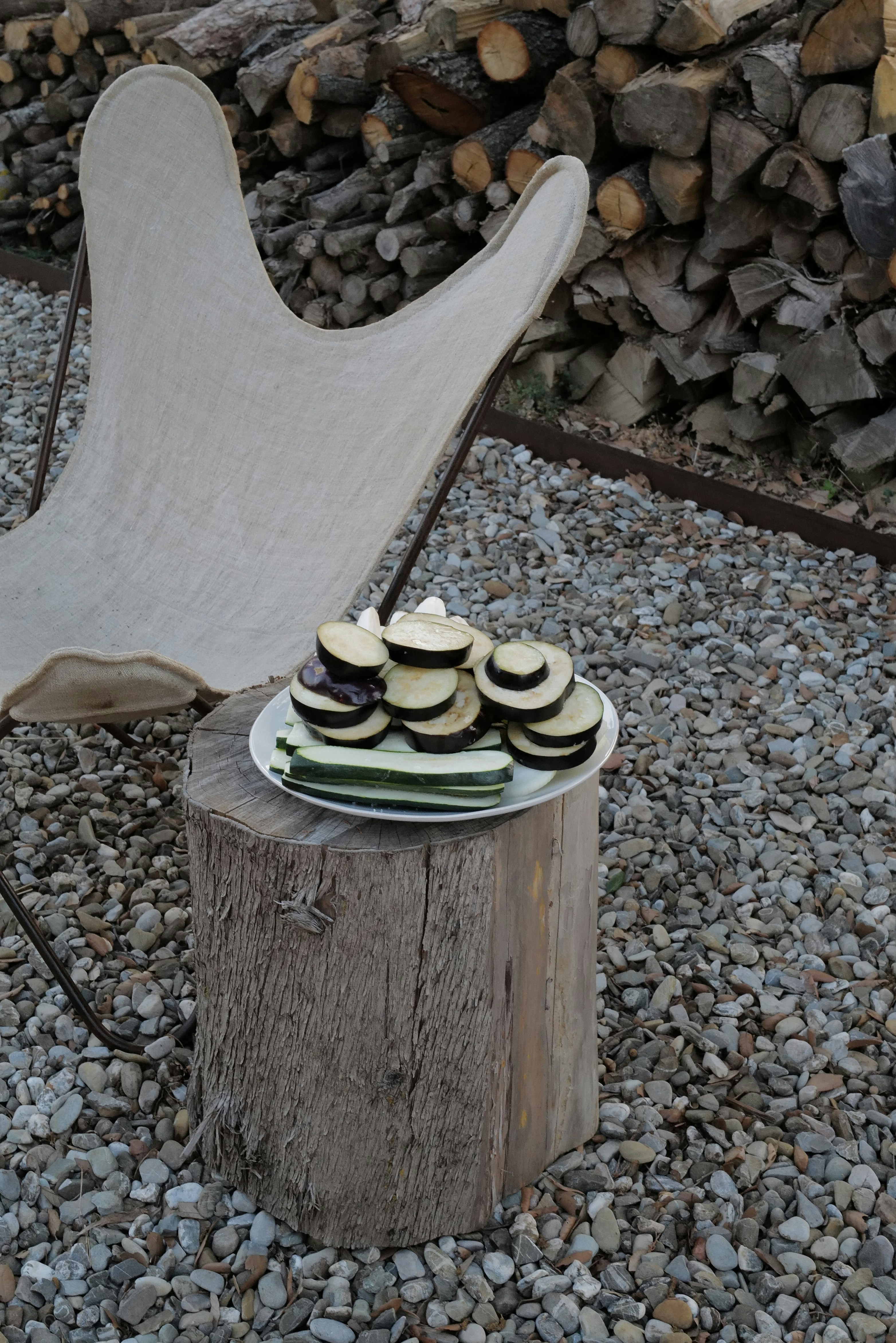 Eggplant and zucchini await grilling on a wooden stump.