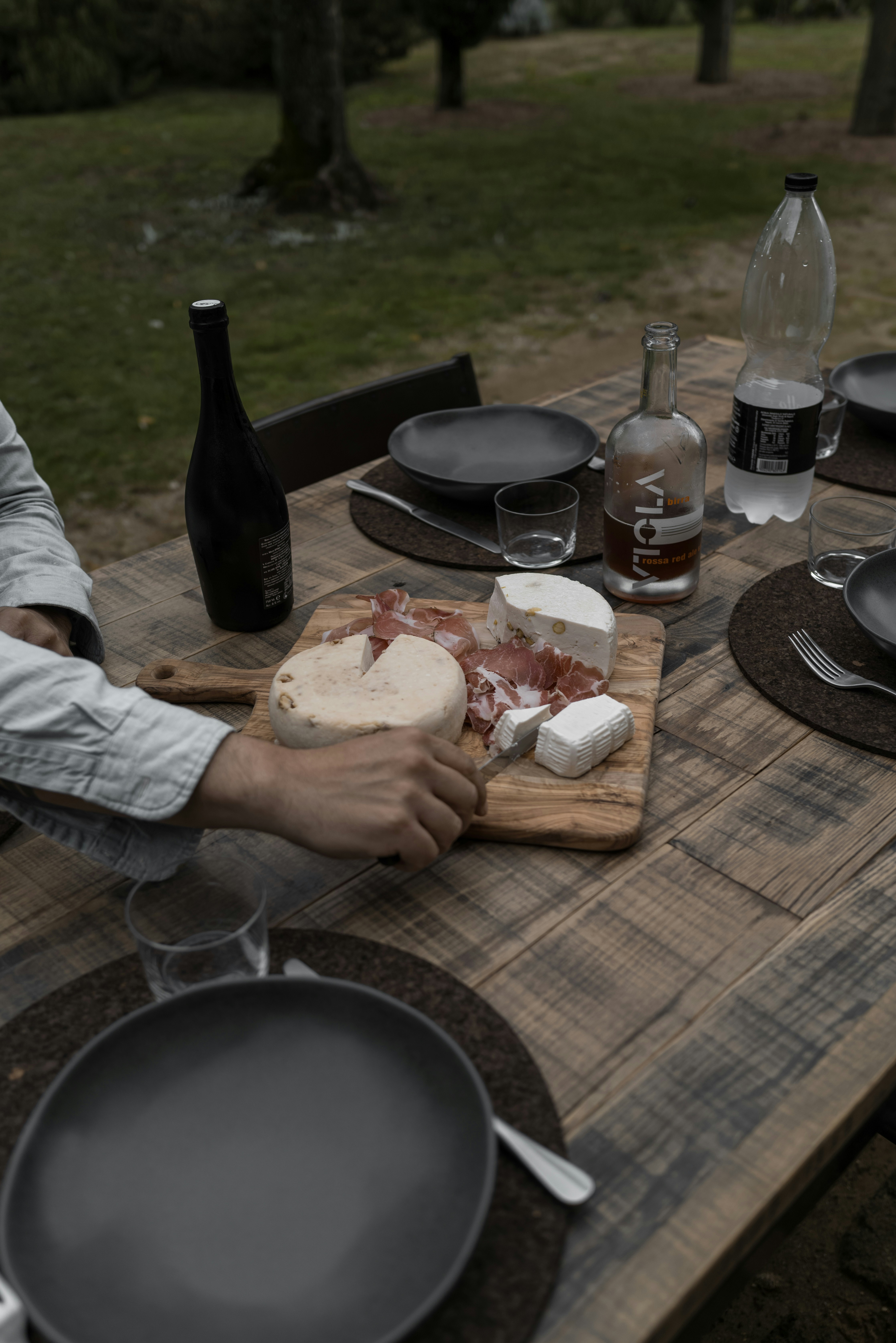Cheese, wine, and plates on a rustic table.