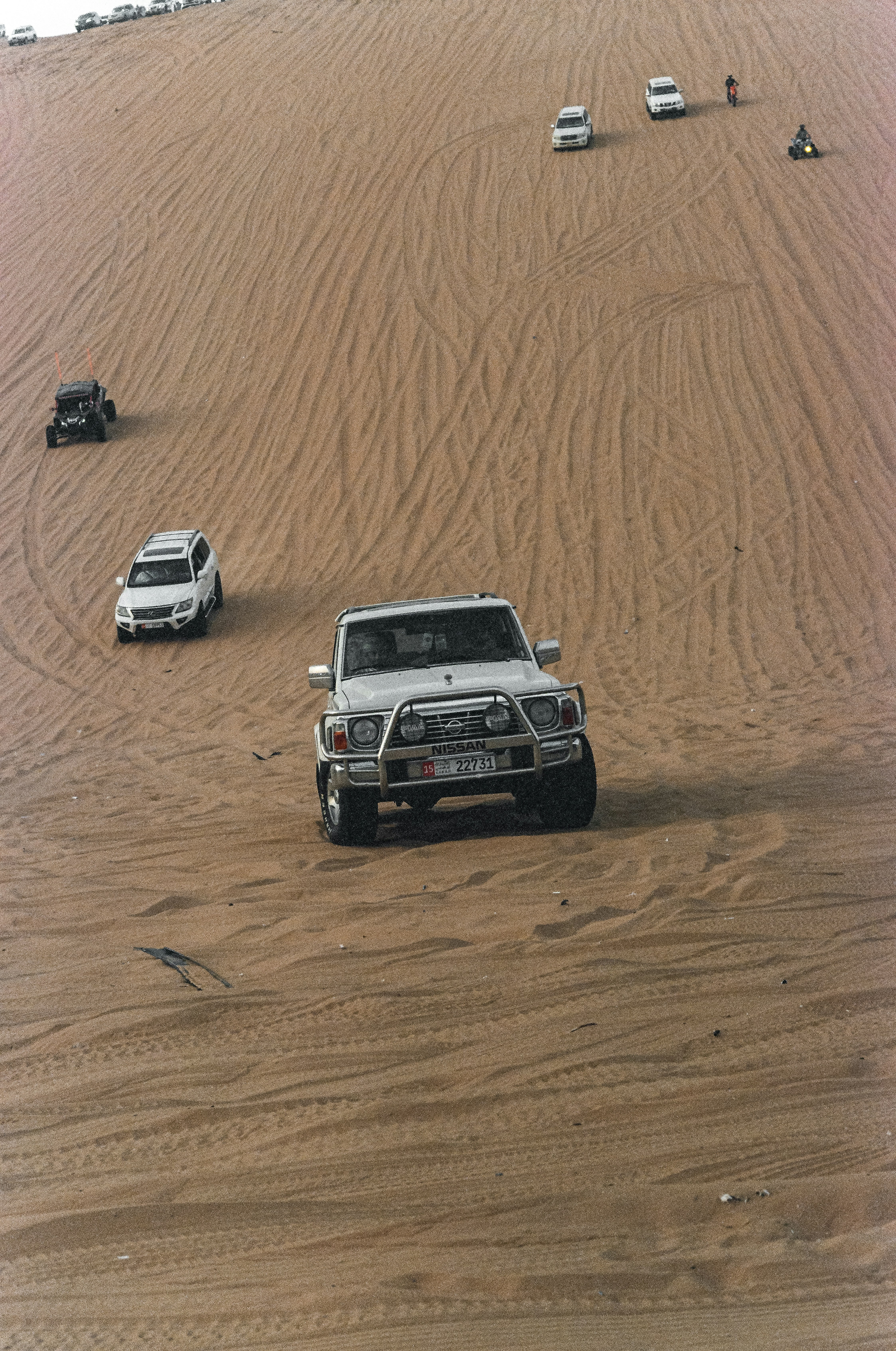 Cars are driving on a sandy dune.