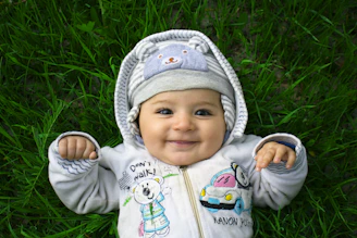 Smiling baby lies on the grass, looking happy