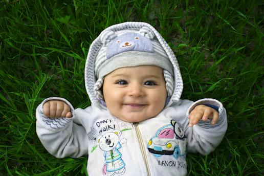 Smiling baby lies on the grass, looking happy