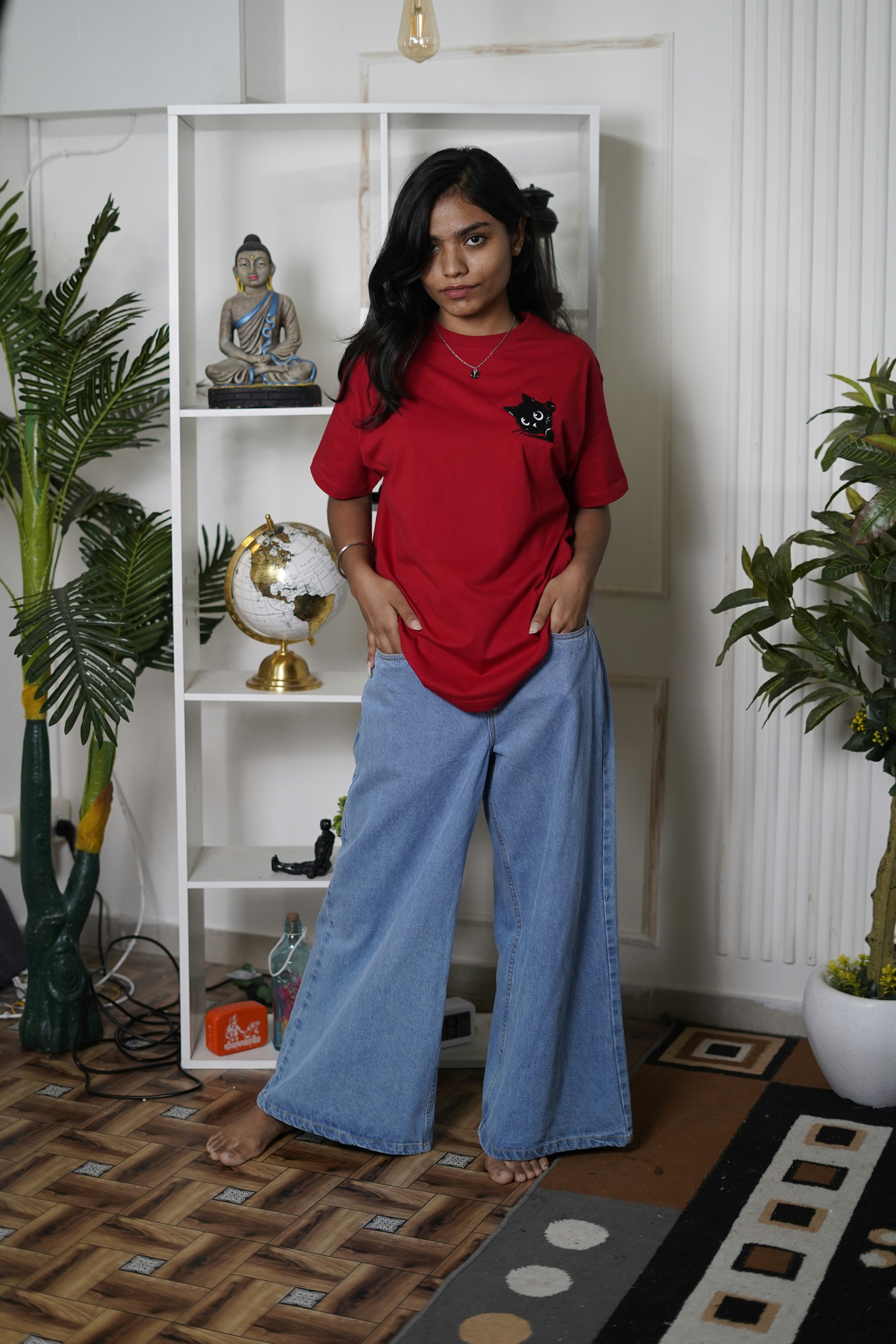 Femme en chemise rouge et jean pose avec désinvolture