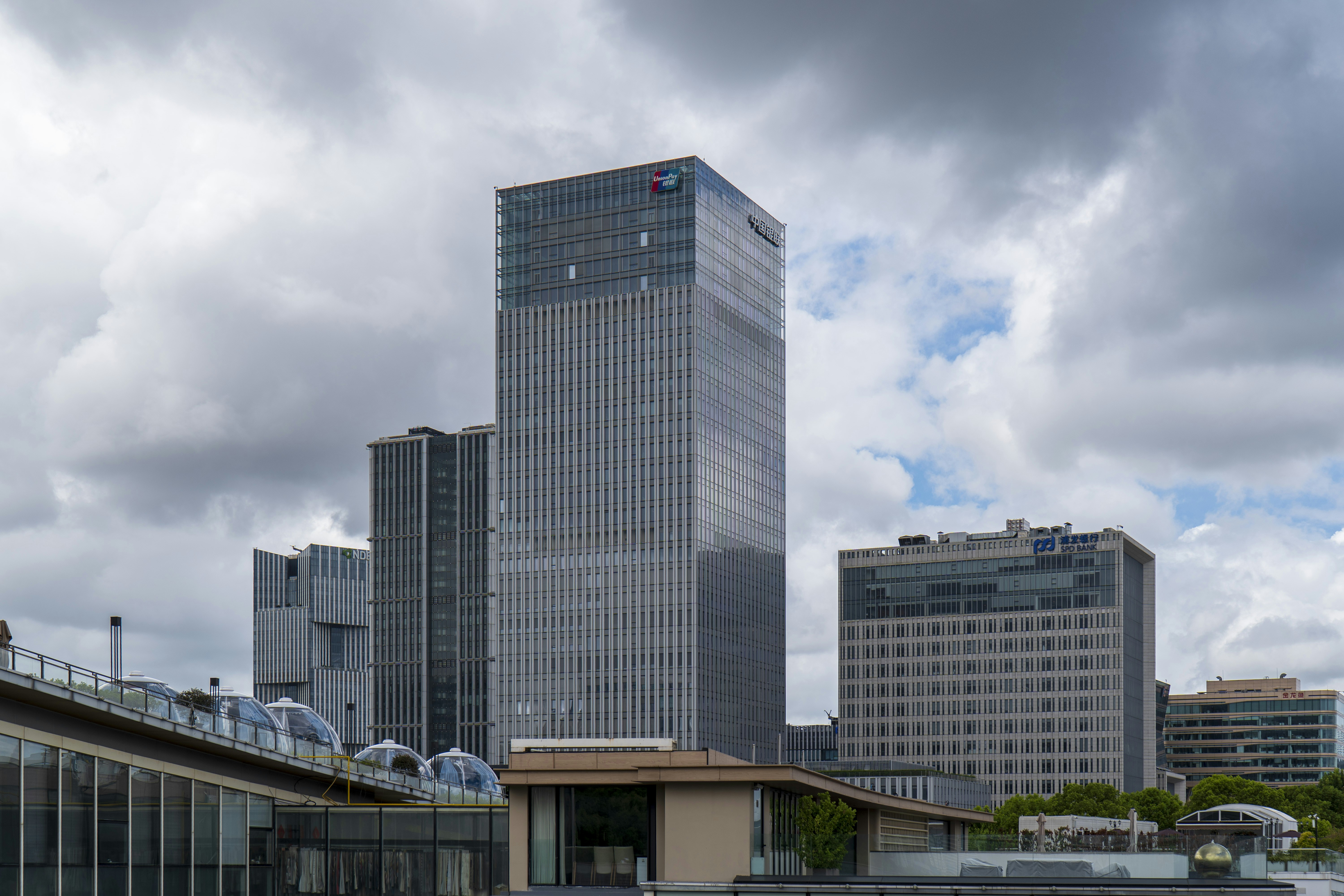 Skyscrapers stand beneath a cloudy, overcast sky.