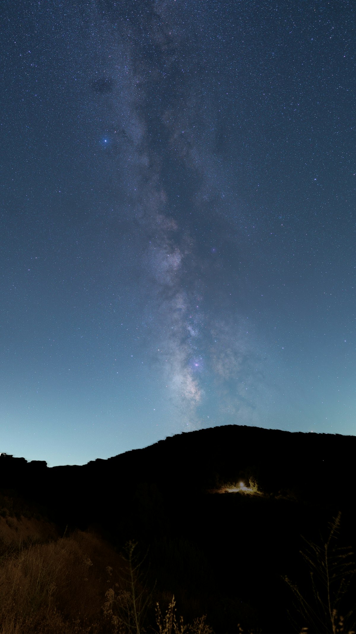 The Milky Way core blazing above a dark mountain silhouette with exceptional star detail from tracked long exposure