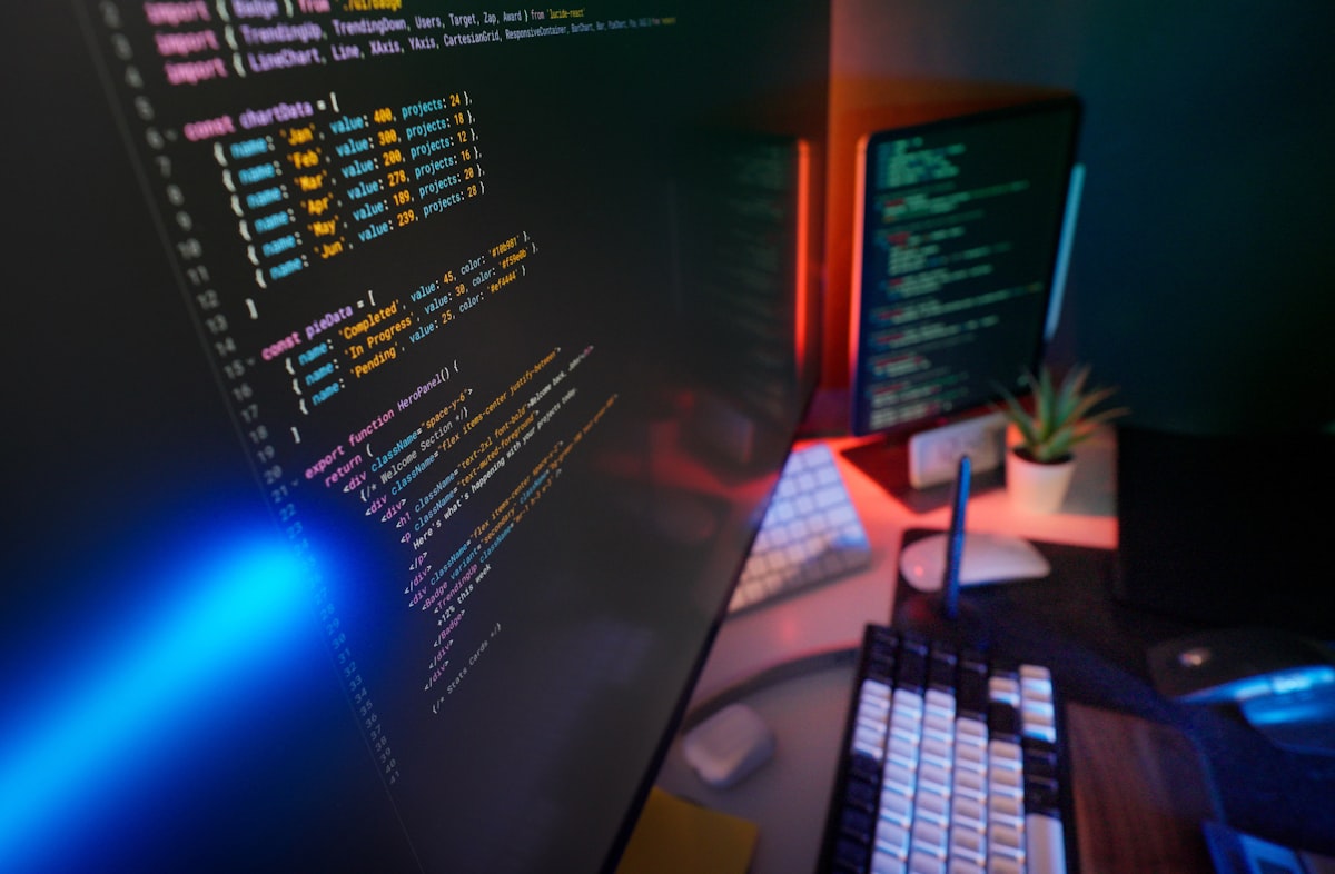 Coding code on multiple computer screens with colorful syntax highlighting