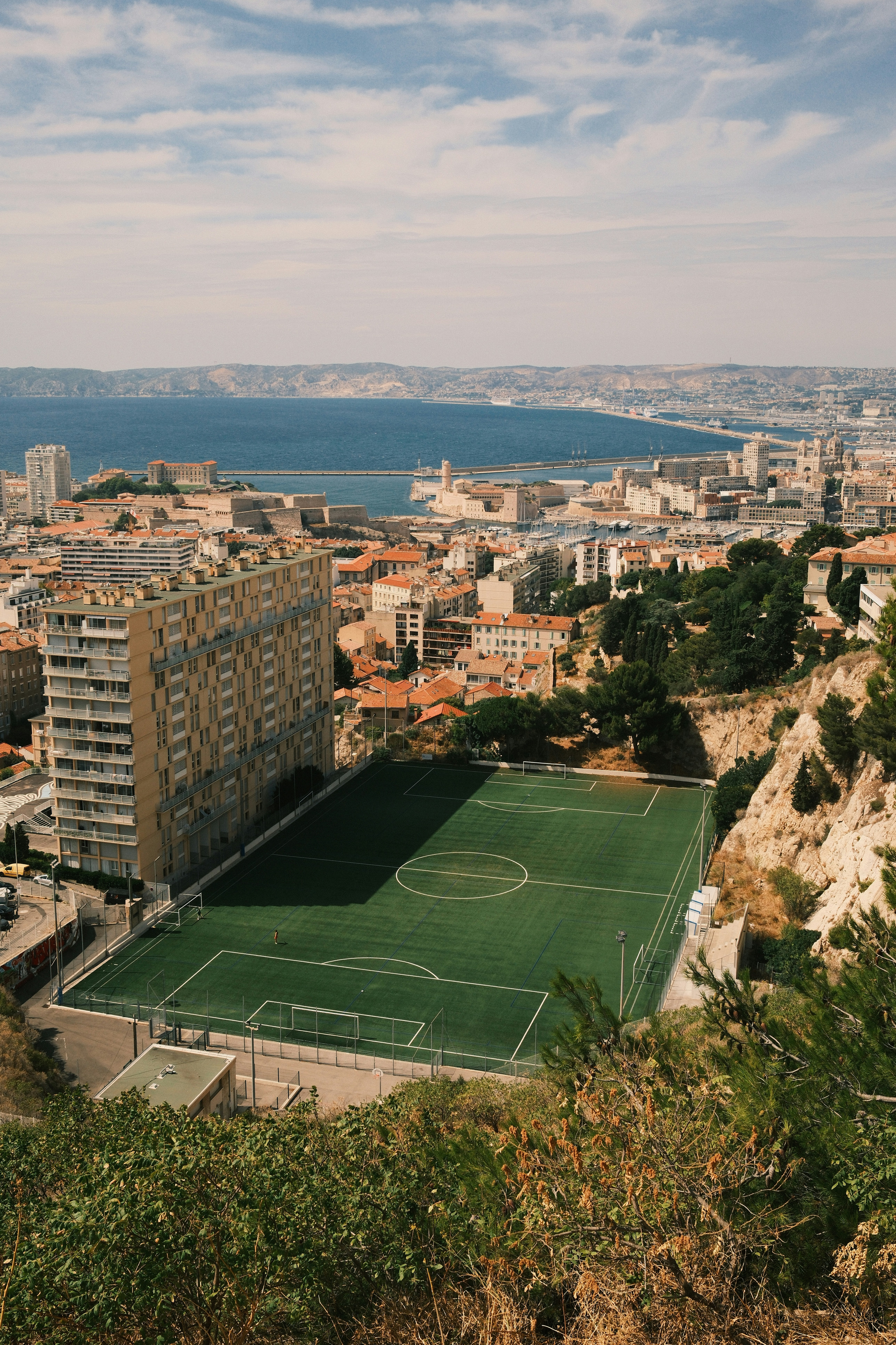 A soccer field overlooks a city and the ocean.